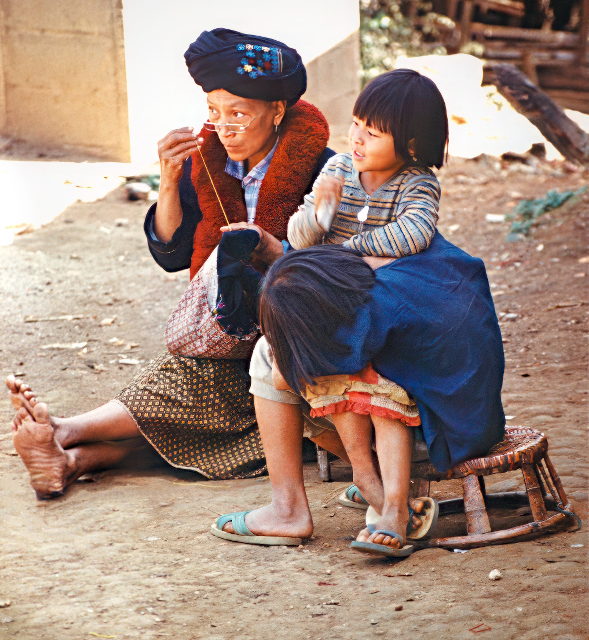 A distraction pulls a small girl’s attention from a sewing lesson – Chiang Rai, Thailand