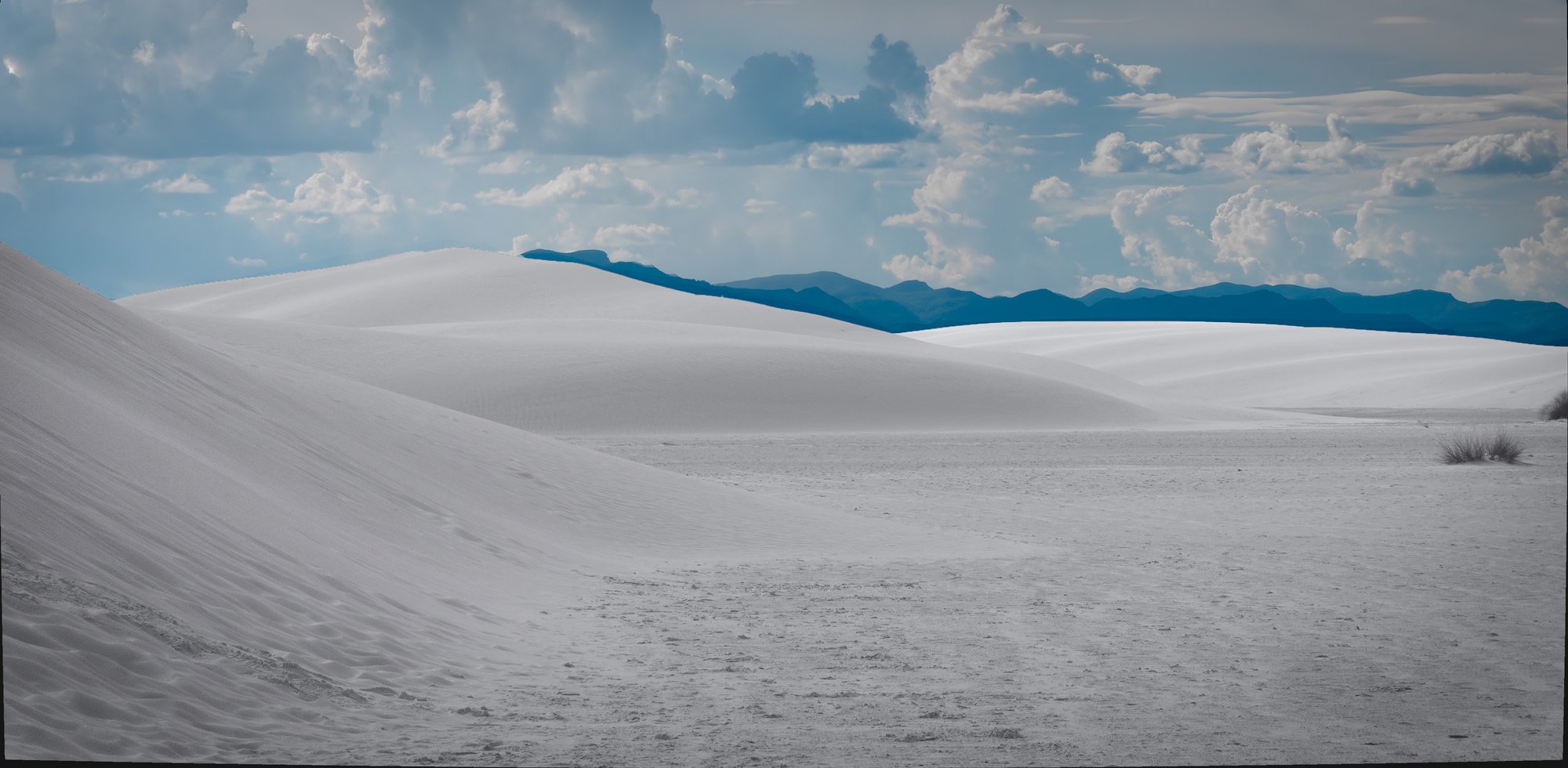A distant storm gathers over the San Andres mountains overlooking the curvaceous dunes of White Sands, New Mexico.