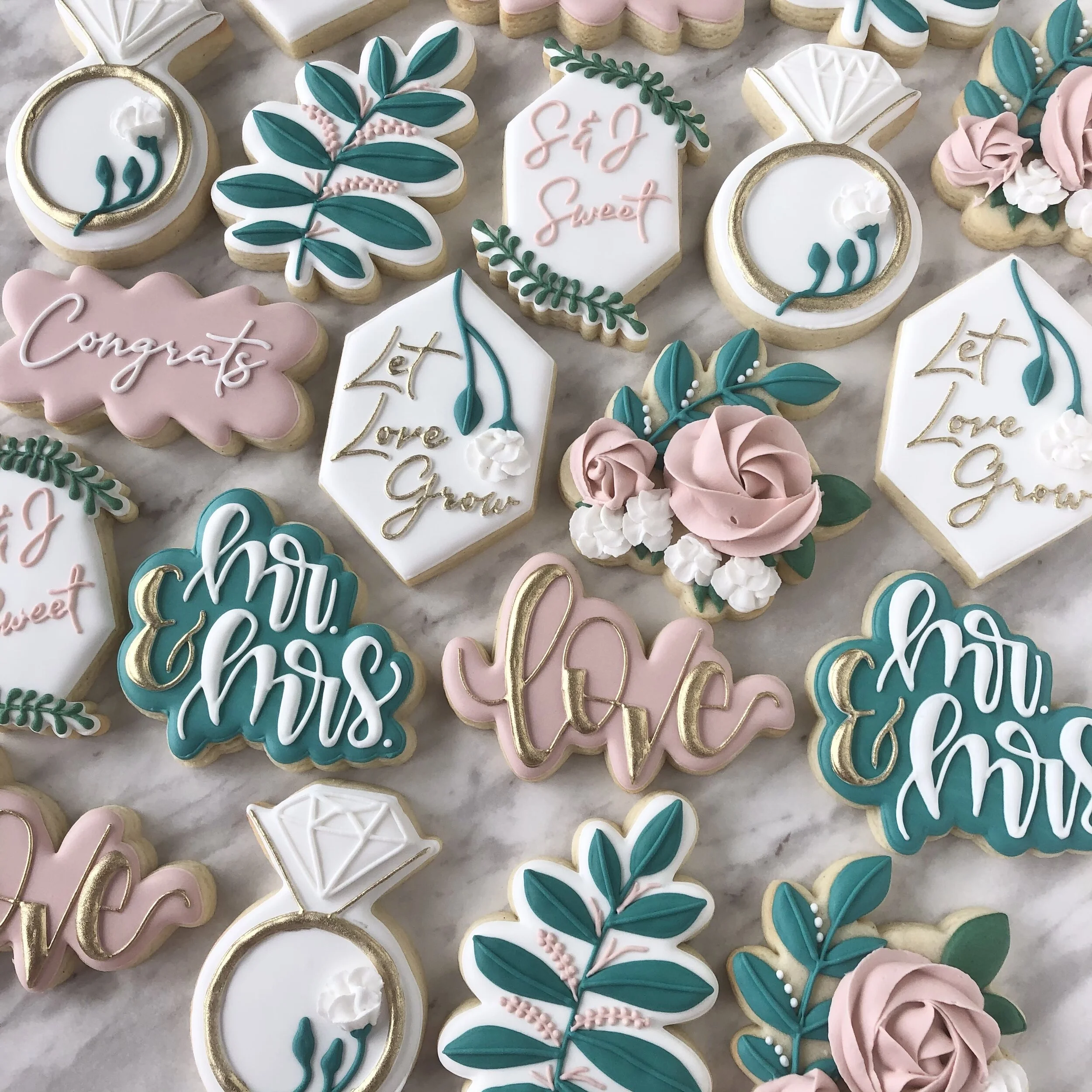 Custom locally handmade wedding favour cookies with messages like "Congrats," "Let Love Grow," "Mr & Mrs," "Love", featuring floral designs, foliage, and ring designs in pastel colors.