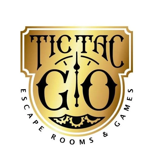 Logo for Traffic Gio featuring a shield design with a clock, gears, and the text "Traffic Gio" and "Escape Rooms & Games."