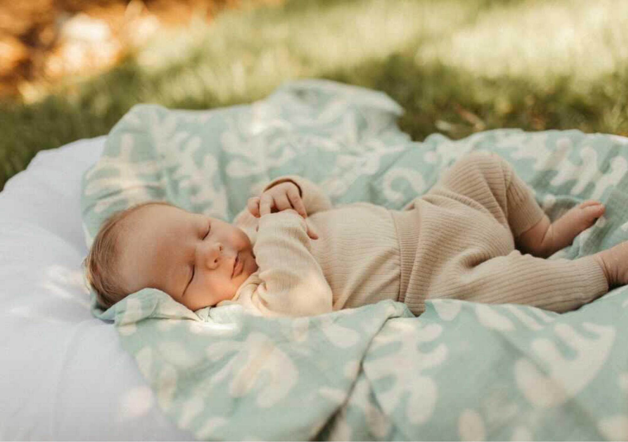 a baby in golden child lounger and marine green swaddle