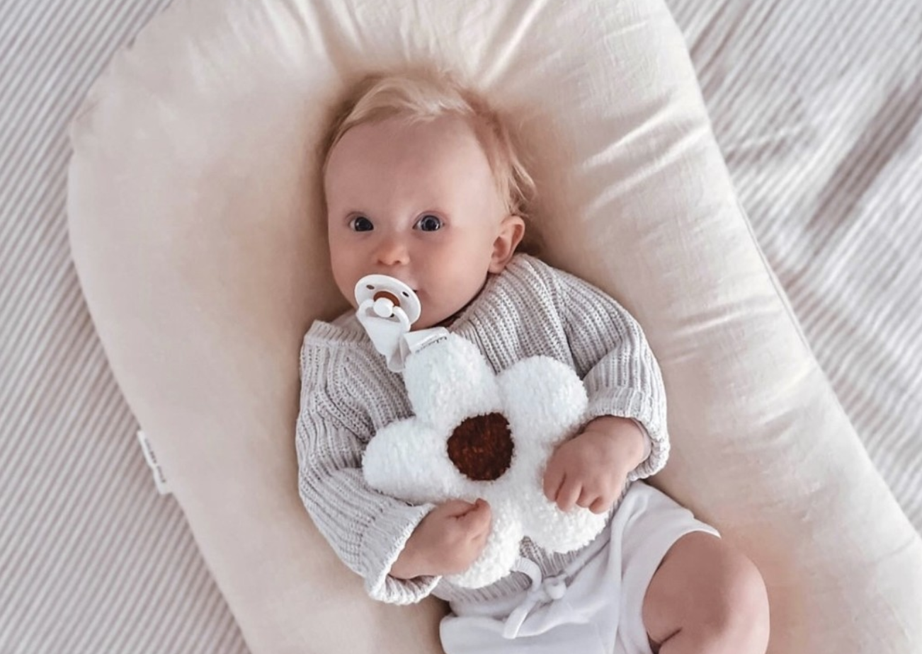 A baby in a white baby nest or lounger