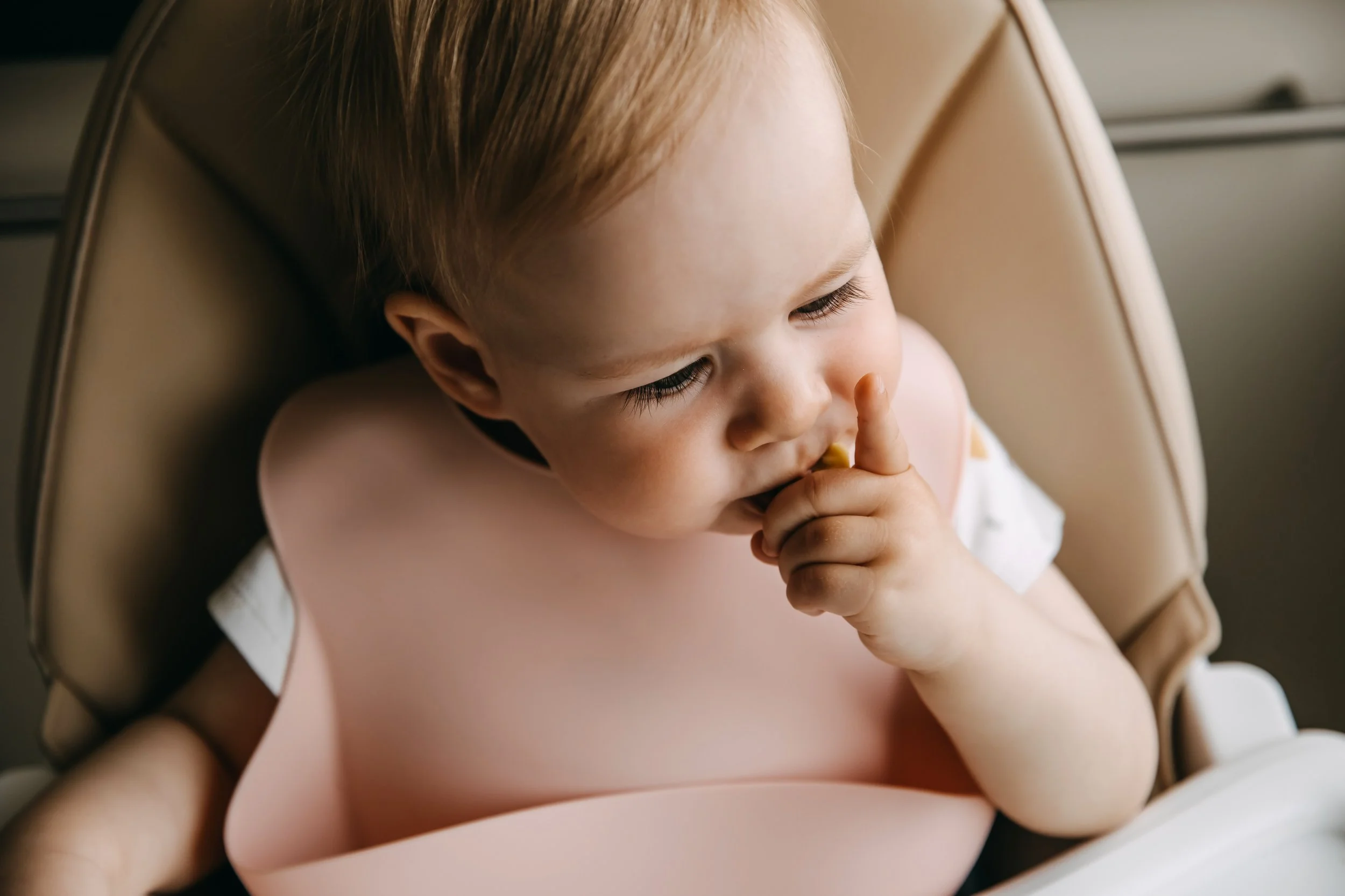 a baby wearing golden child silicone bib in pink colour