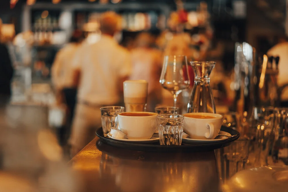 Tisch in einem Café mit Kaffeetassen, Wassergläsern und einem Latte Macchiato.