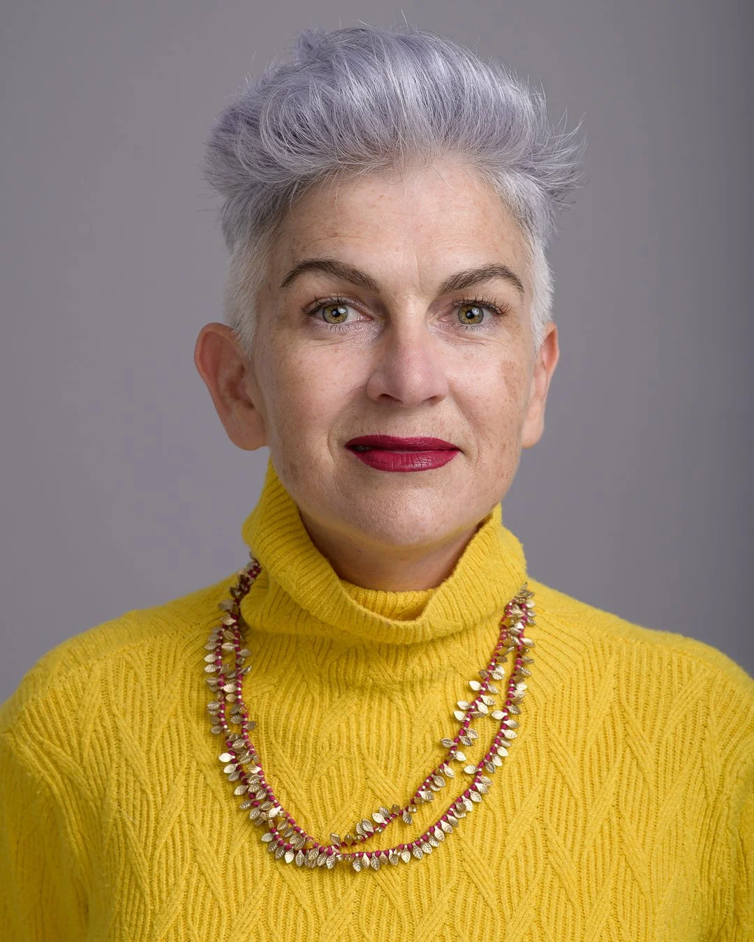 Studio headshot portrait of a woman with short silver hair for a Cape Town design business.