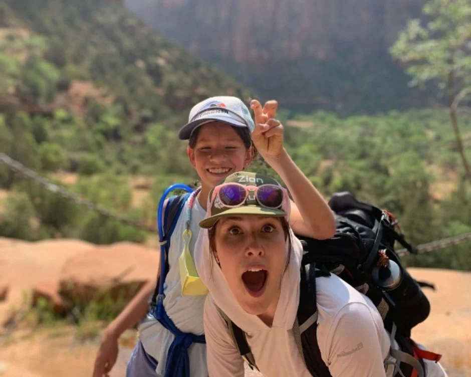 A tour participant puts bunny ears over their guide's head while hiking in zion