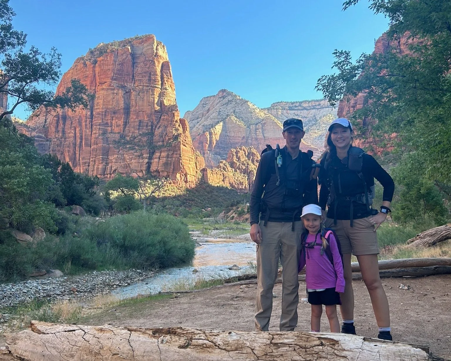 A man, woman and child smile along a river while hiking in zion