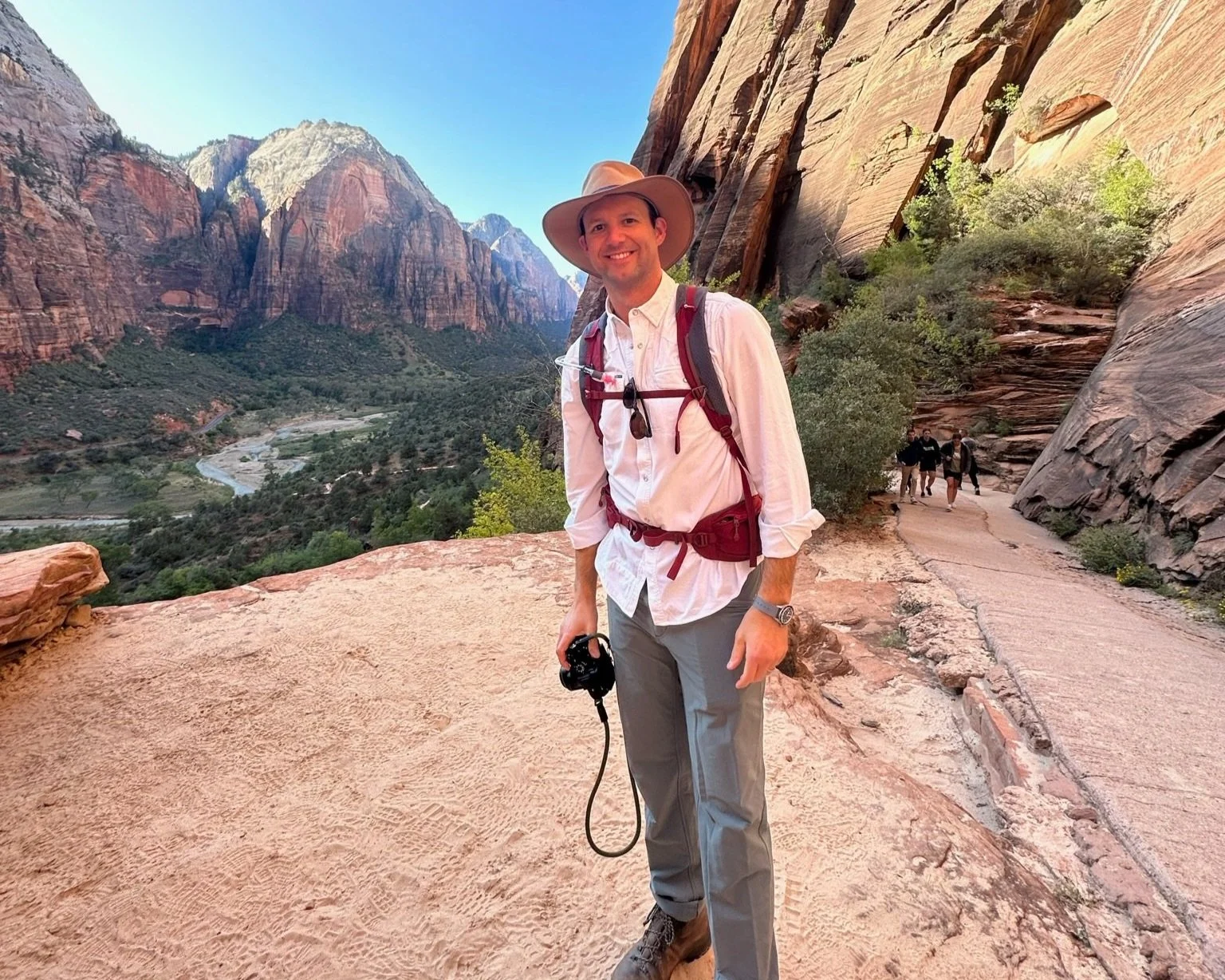 A man with a hat and camera on a zion hiking tour