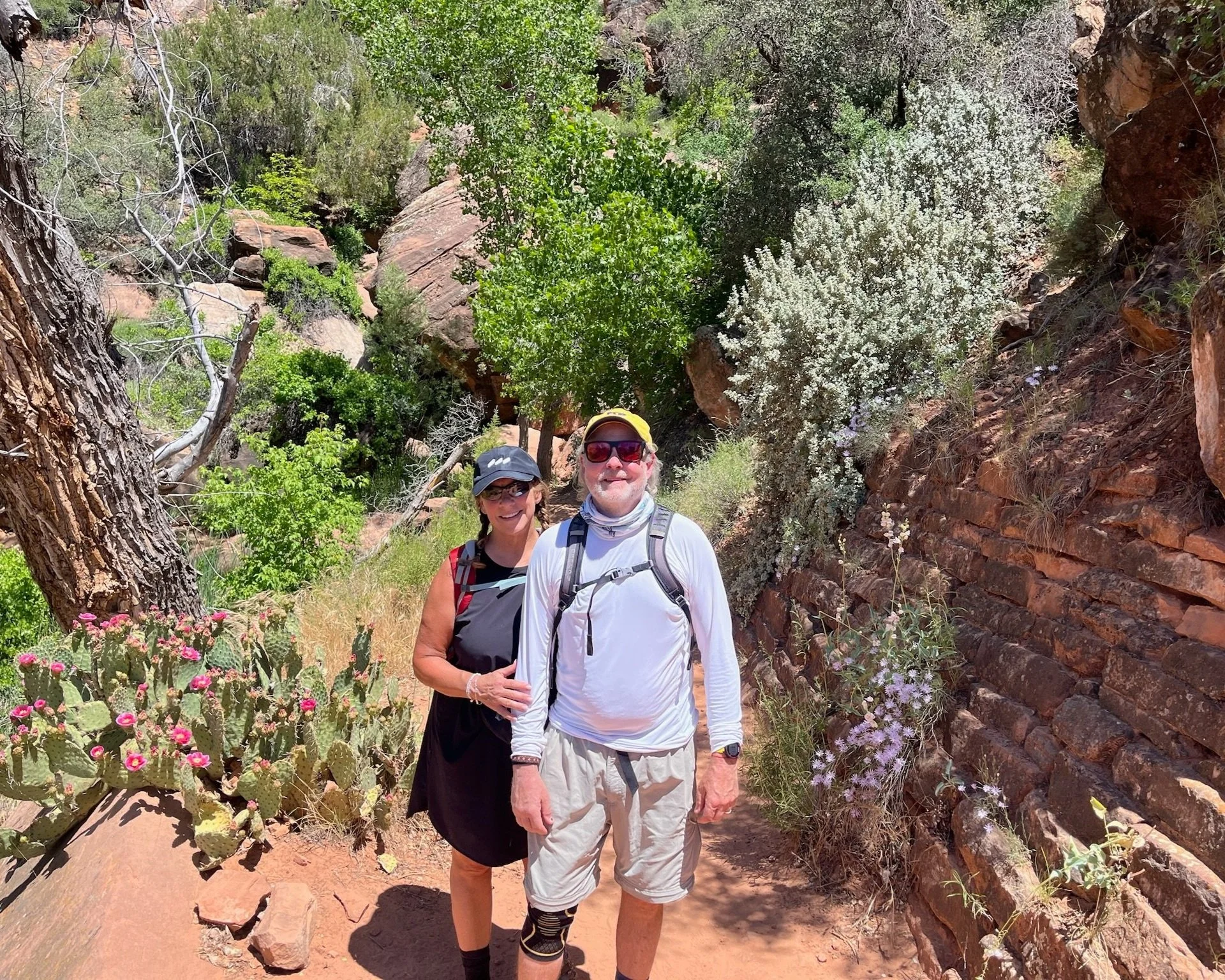 A man and woman hiking next to cactus in zion