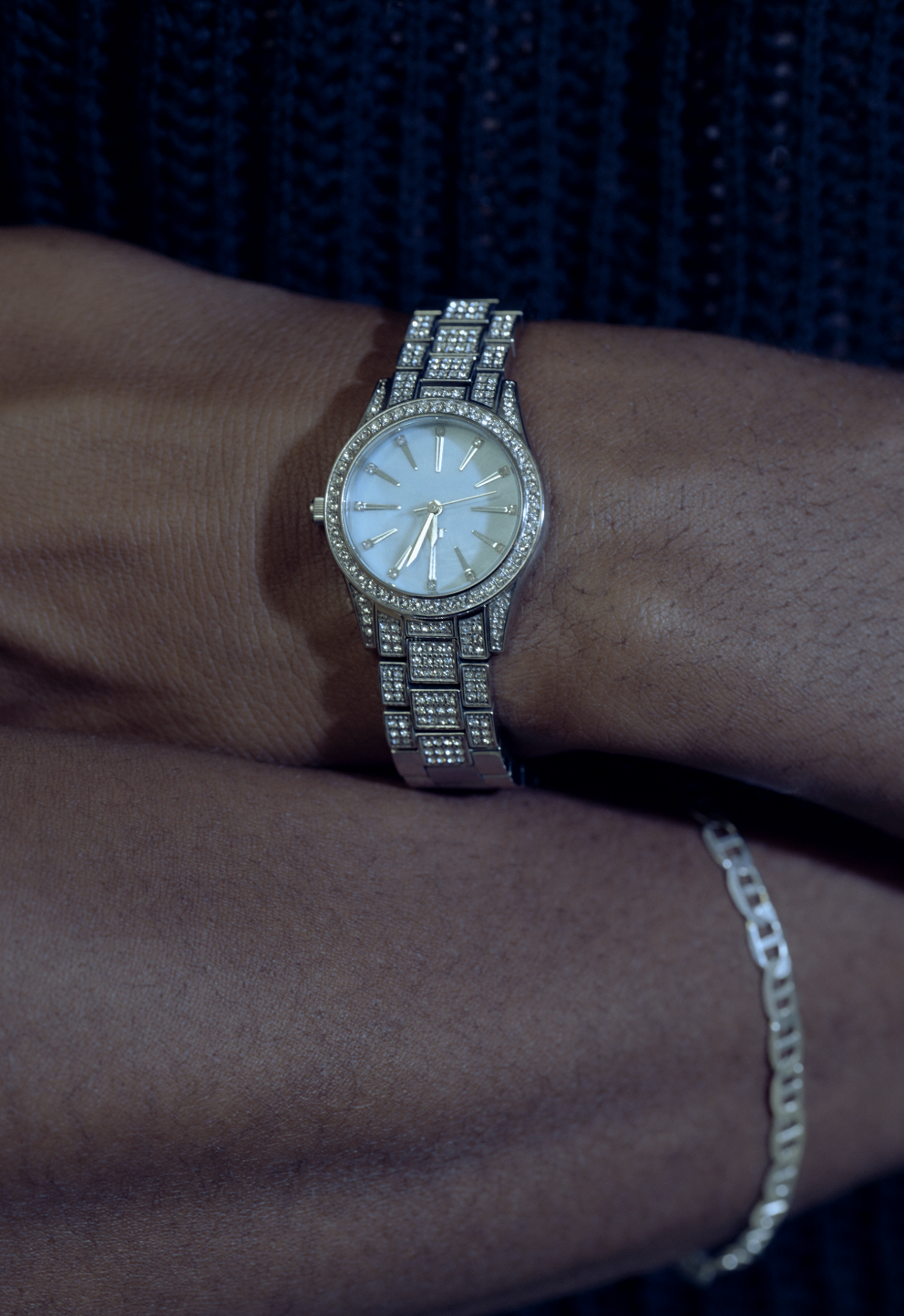 A person wearing a silver wristwatch with a white face and a bracelet, viewed from the side.