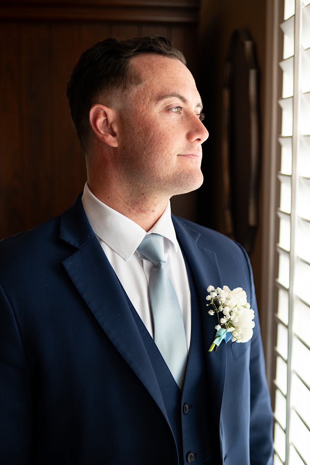 Groom Cameron smiling in his wedding suit on his wedding day.