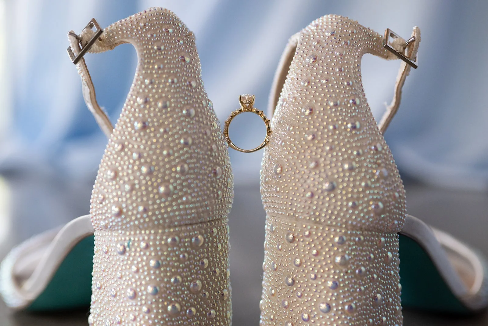 Bride's ring and wedding shoes photographed in a romantic close-up.