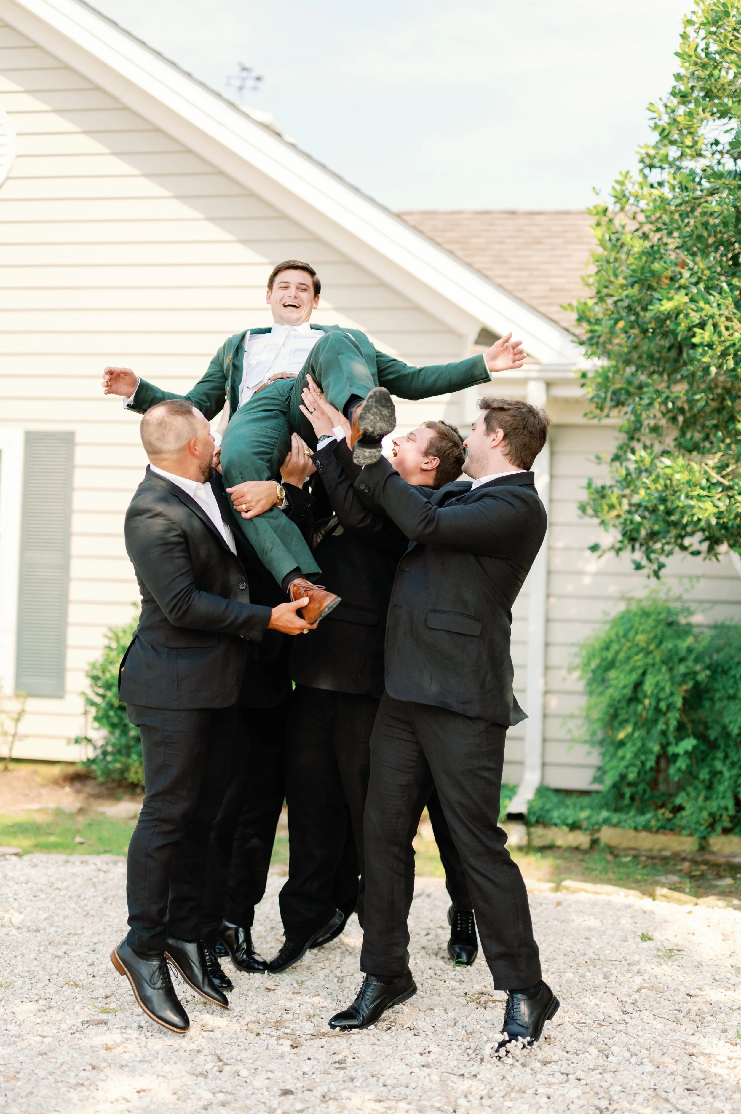 Groom gets thrown in the air while smiling by his groomsmen