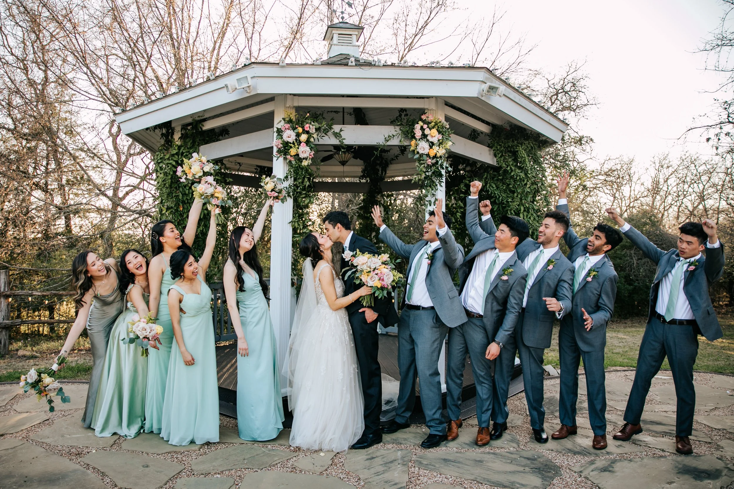 Bride and groom kiss at the alter at the Outdoor wedding ceremony space surrounded by trees and greenery