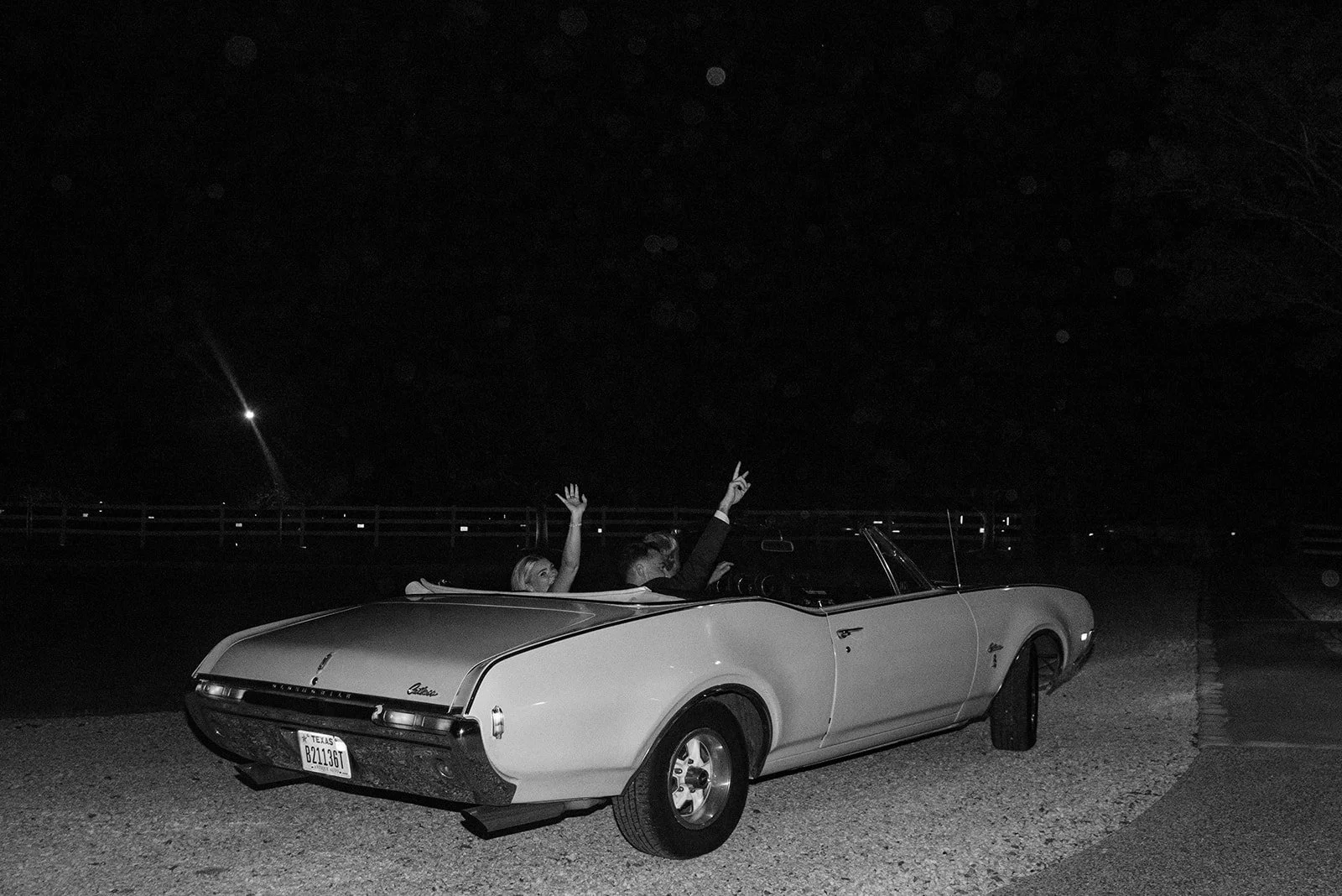 Cameron and Makenzie driving away together in a vintage car after their wedding celebration.