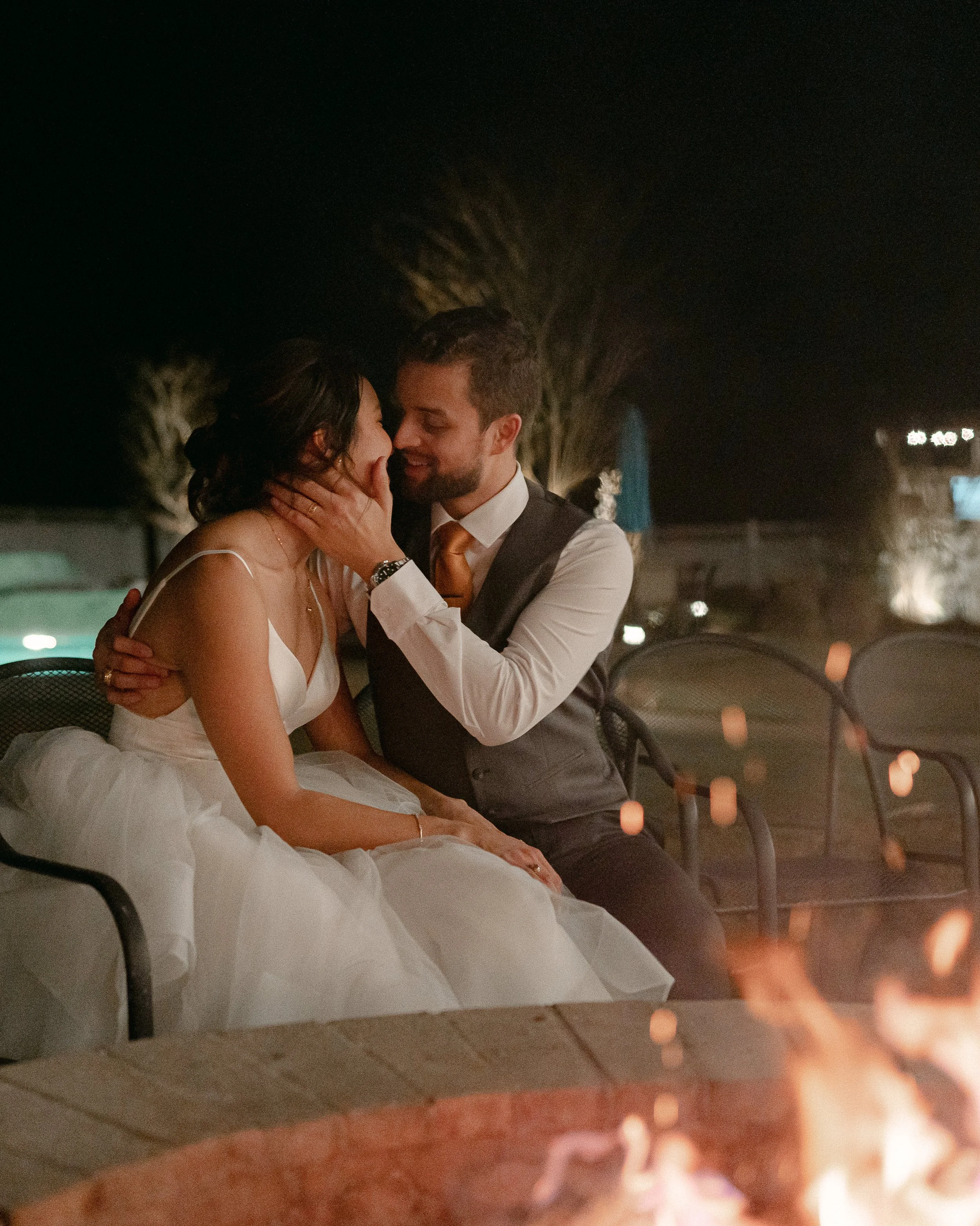 Bride and groom share a private romantic moment by the fire during their reception