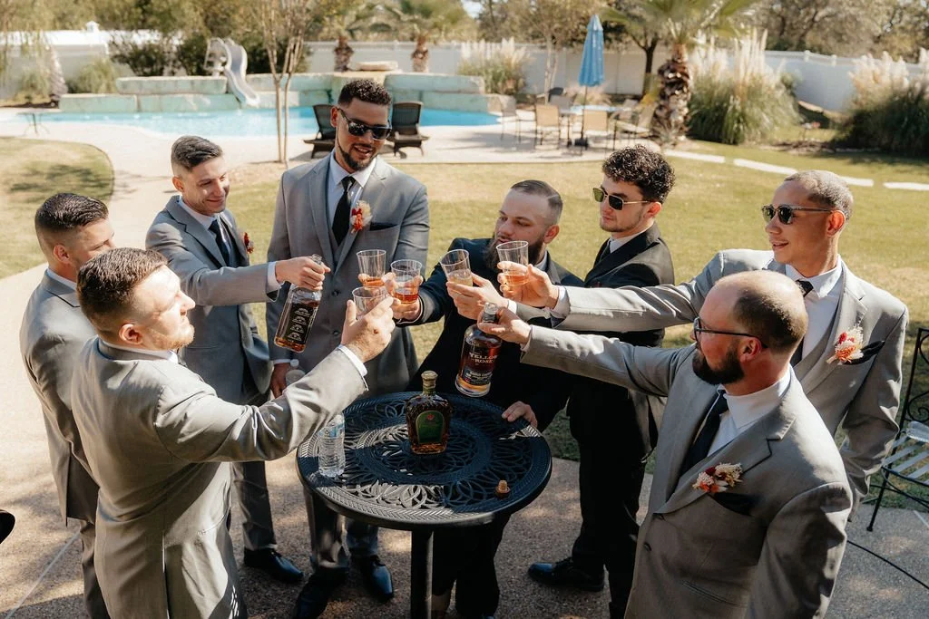 Groomsmen toast groom on wedding day in outdoor reception area