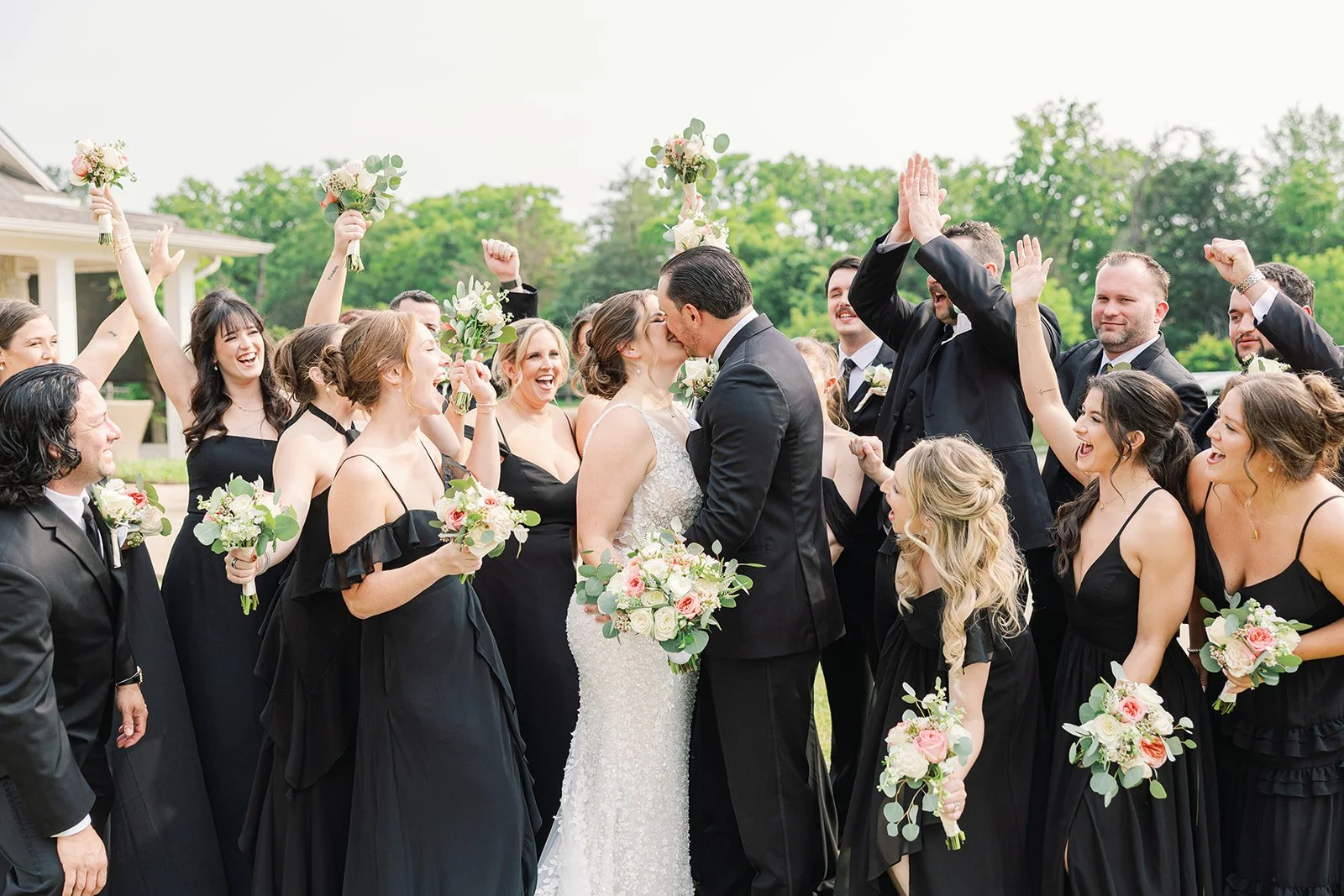 bride and groom share a kiss while wedding party cheer them on in Bryan Texas