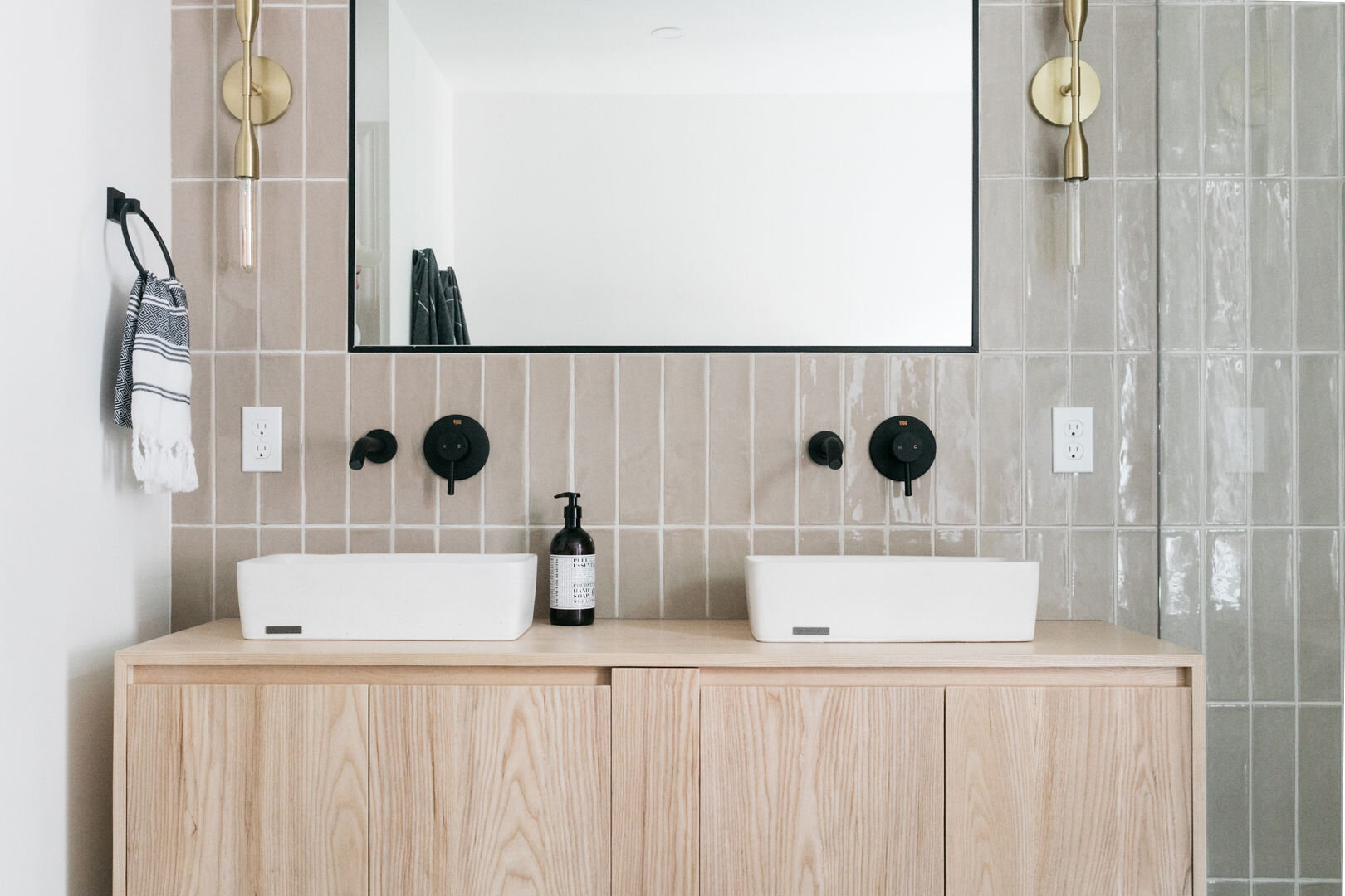 Minimalist bathroom with black pebble floor, natural wood vanity, and European-style design in Nevin St. home.