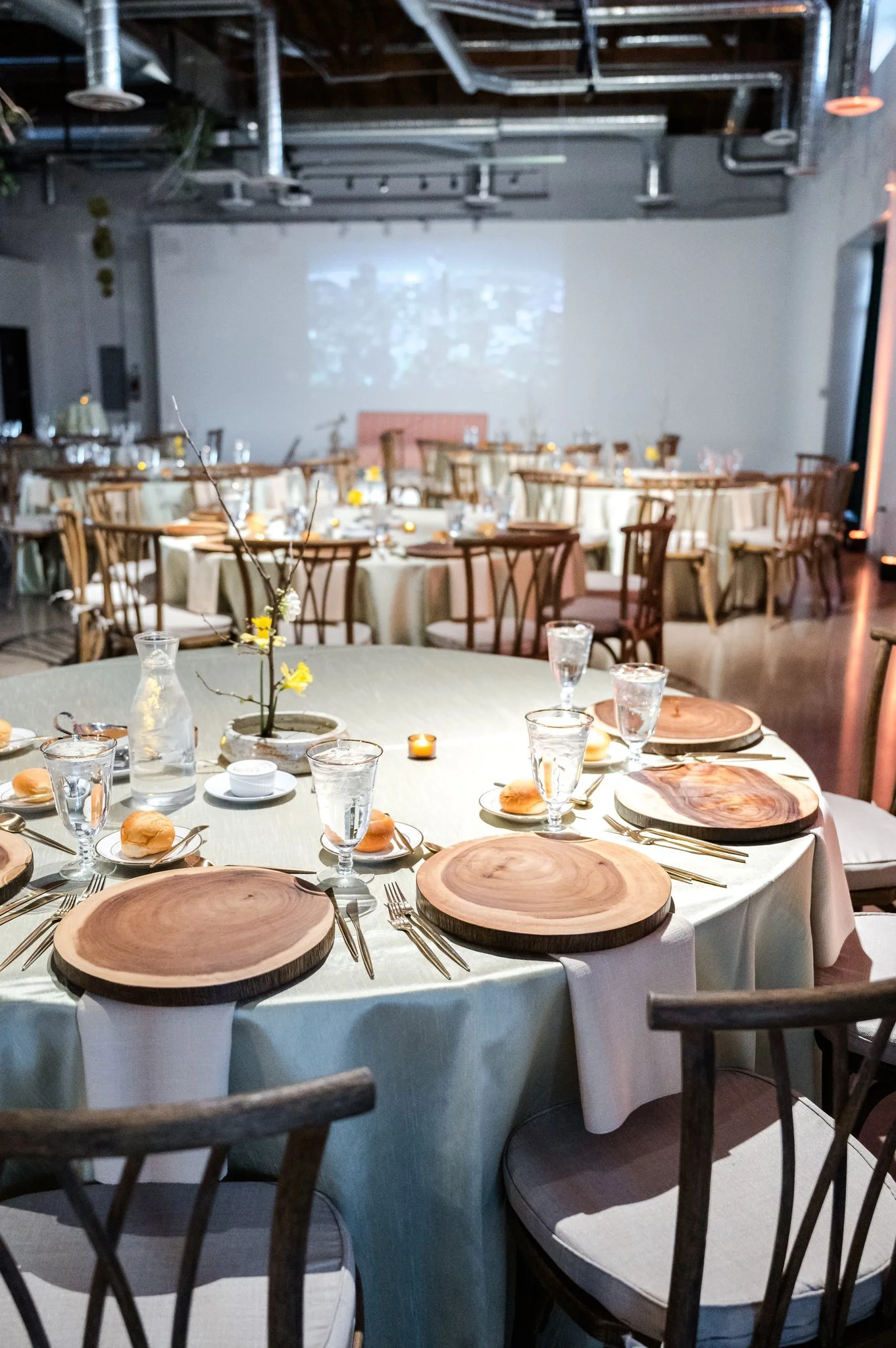 Indoor event space with decorated tables, floral centerpieces, balloon decor, and large illuminated letters spelling 'T BR'.