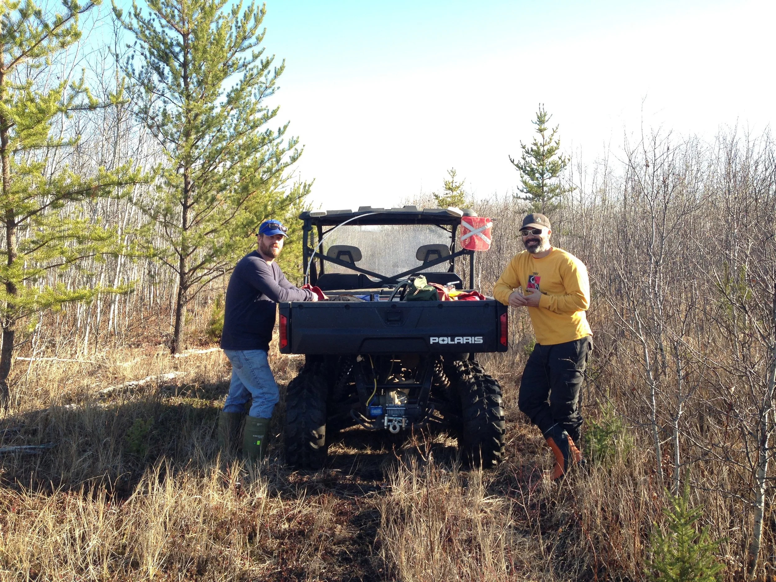 Two men next to an off-road vehicle in a forest