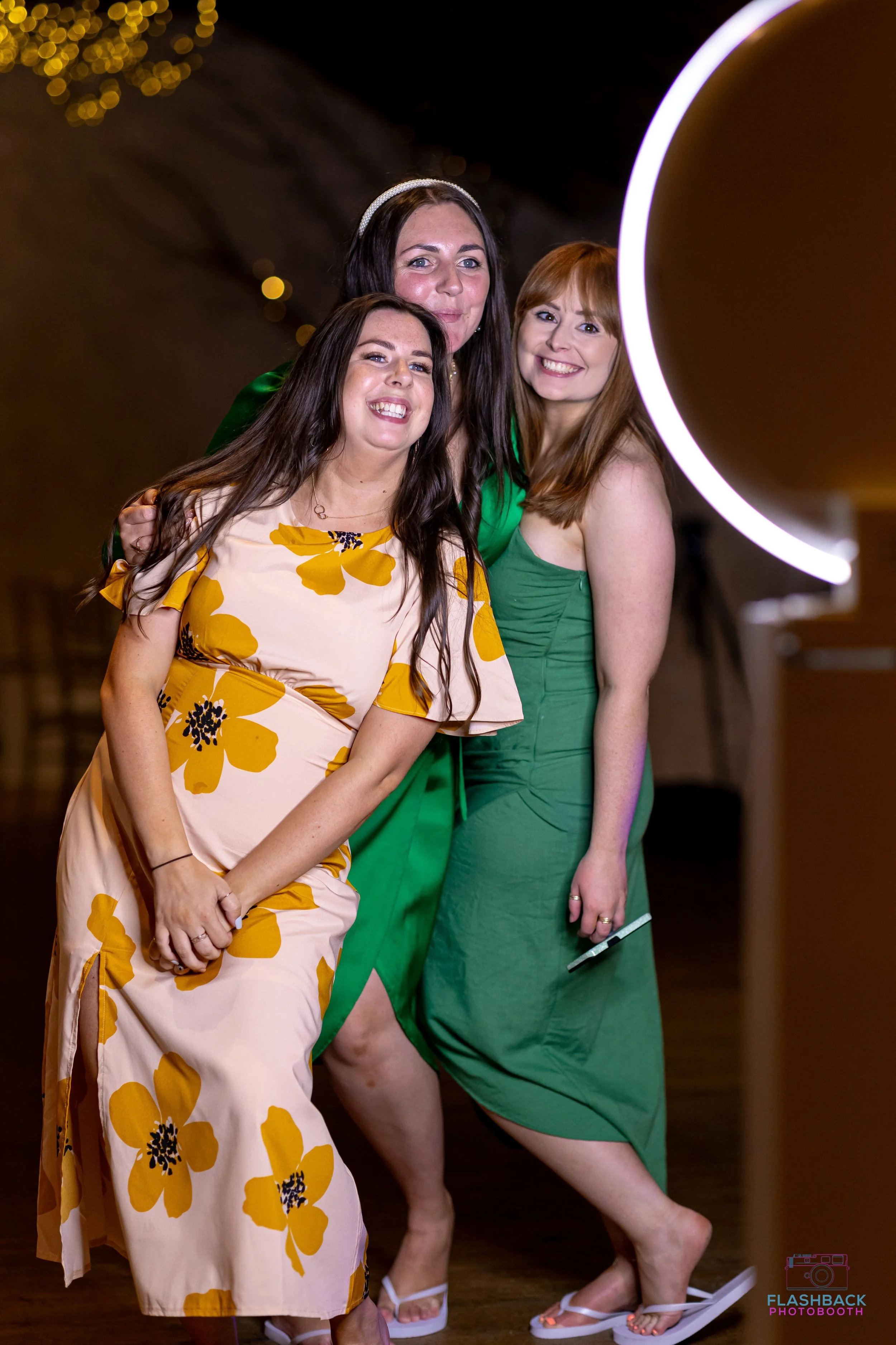 Three women smiling and posing in front of a photo booth
