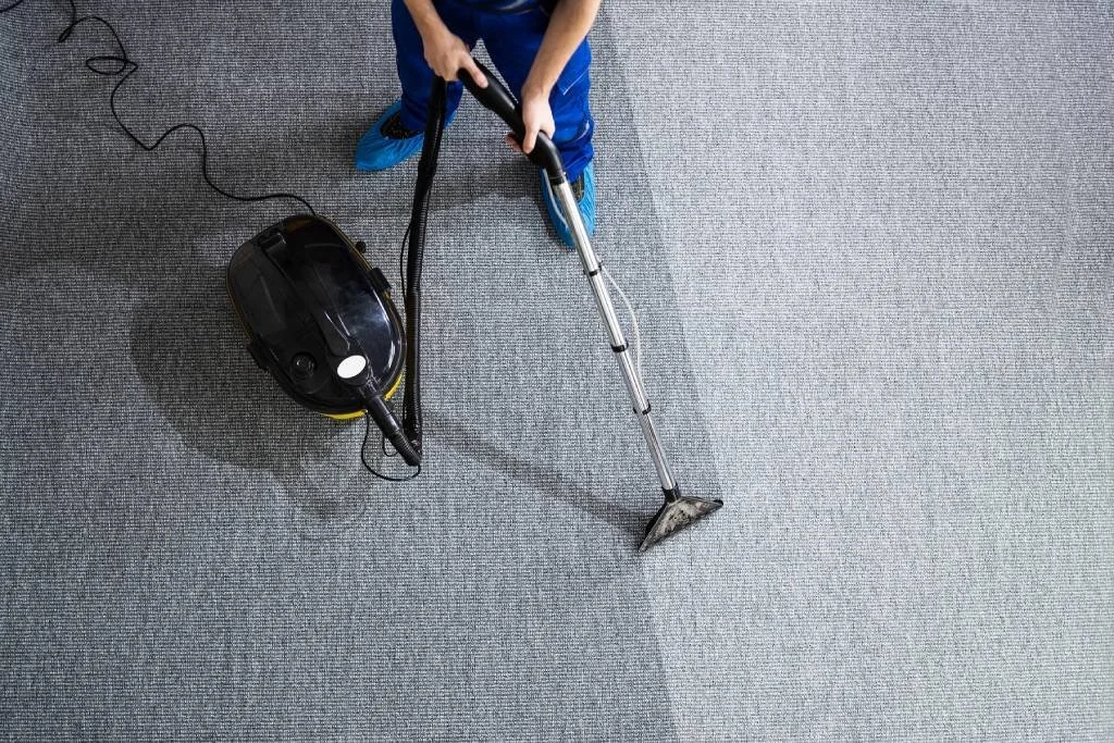 worker vaccuming carpet