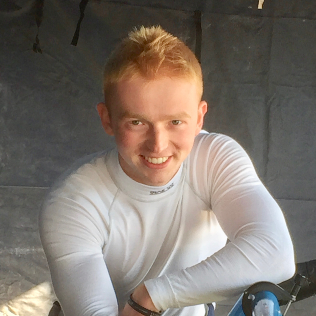 Will Stowell wearing a white long-sleeve shirt, sitting against a dark slate wall.