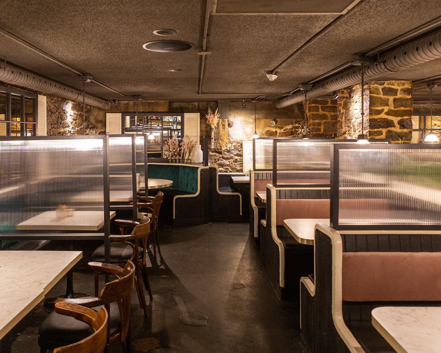Interior of a cozy restaurant with booths and tables, exposed brick walls, and dim warm lighting. velvet booths, sexy interior, private events, parties, Ottawa events, venues, original space, 