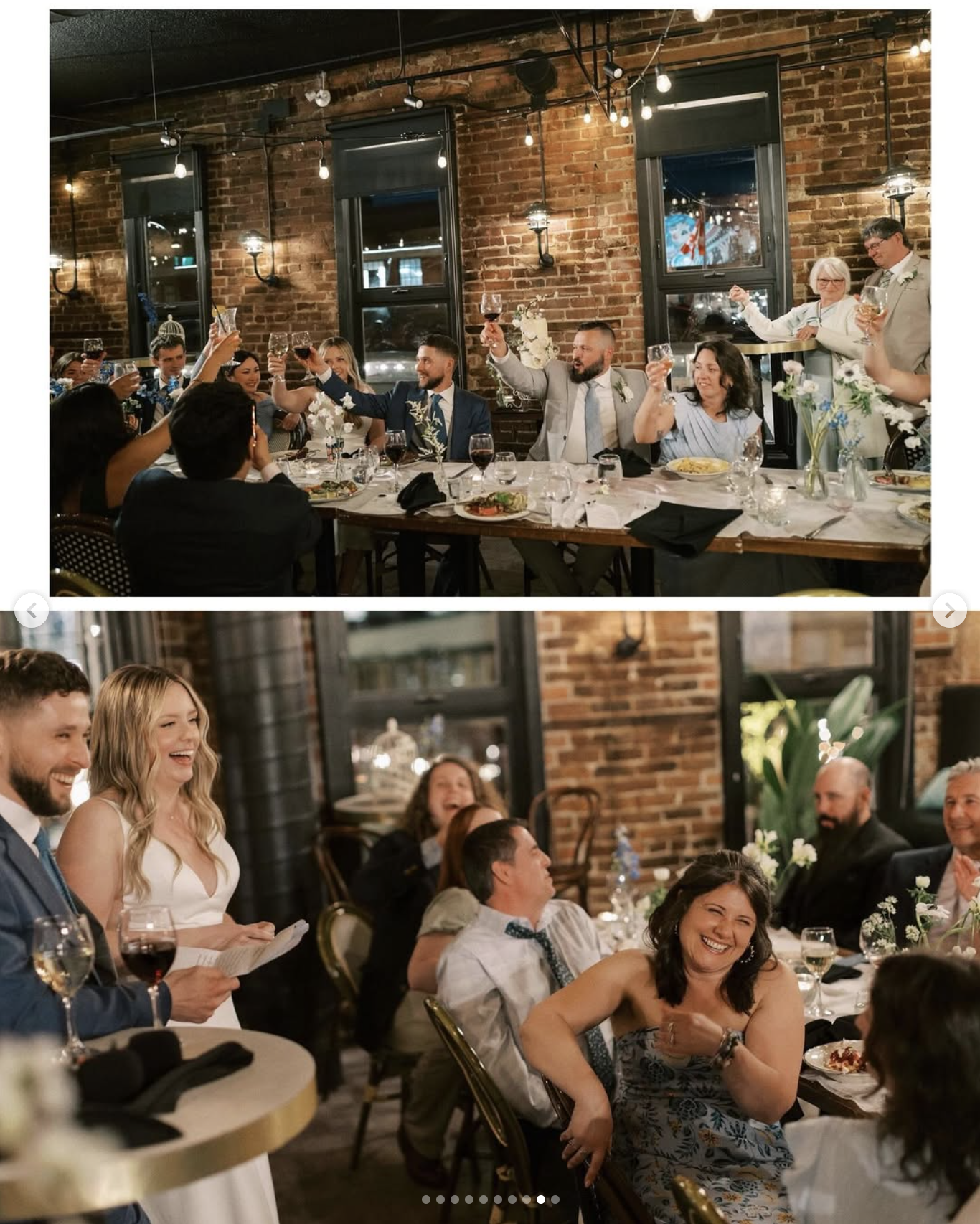 A wedding reception with guests raising glasses in toast, seated at tables decorated with flowers and candles in a brick-walled venue with large windows and string lights.