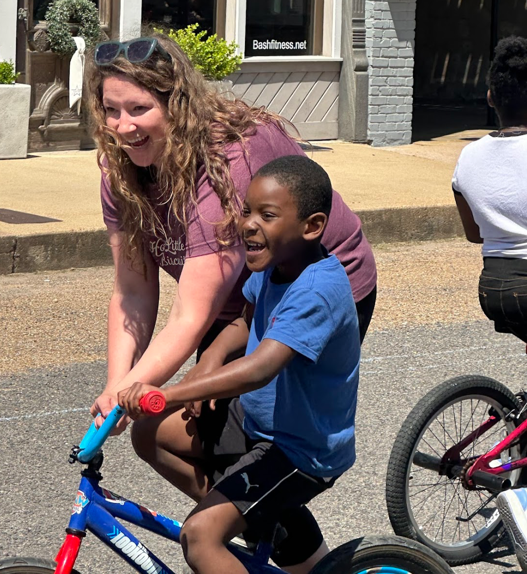 Woman helps a child ride his new bike from studioDRIFT's Bike Incentive Program.