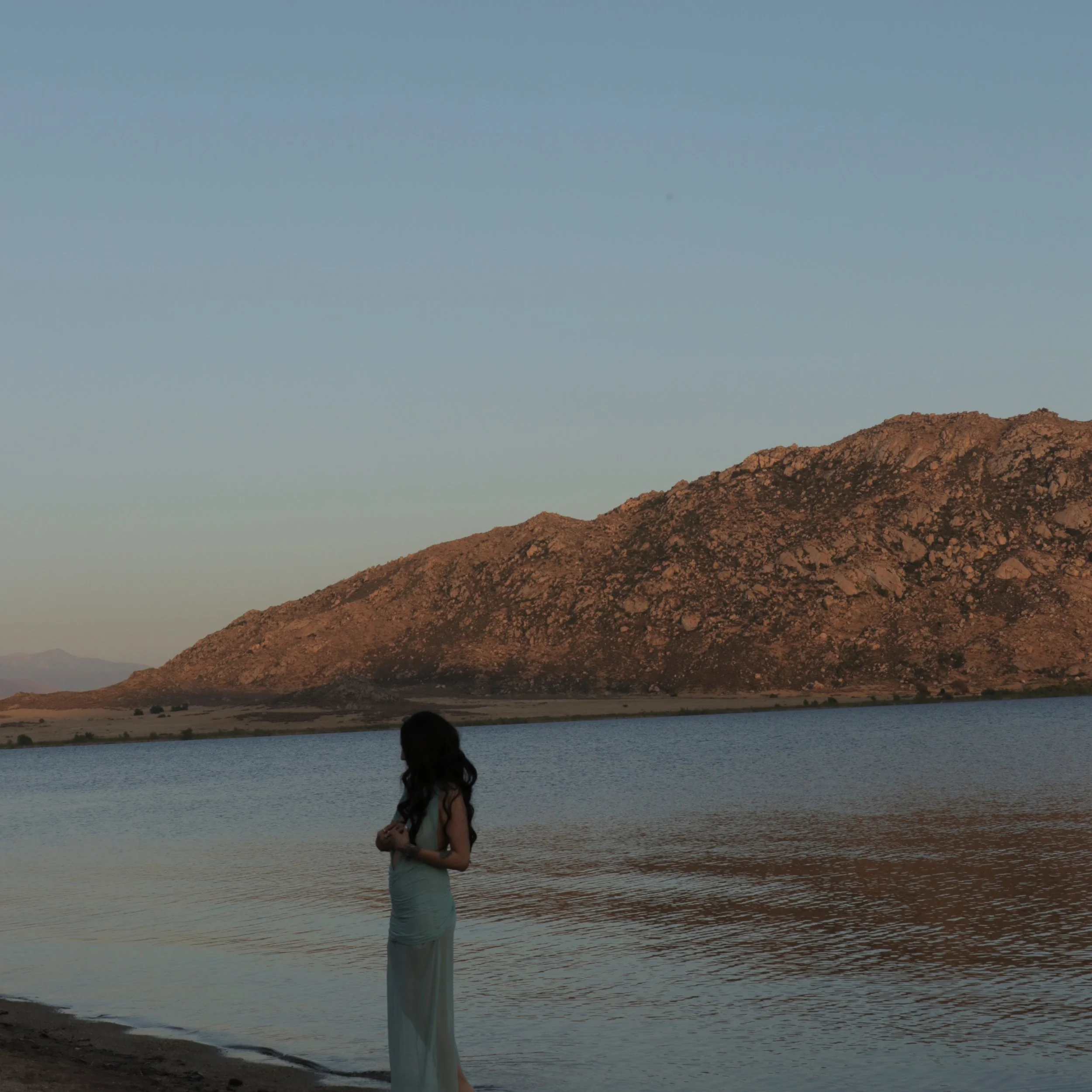 Valiance Sapphire, the Siren-Futurist Dark Pop artist, posing near the water for the Moonlit Siren music video. Cinematic, celestial aesthetic inspired by mythic siren energy and alternative indie rock.