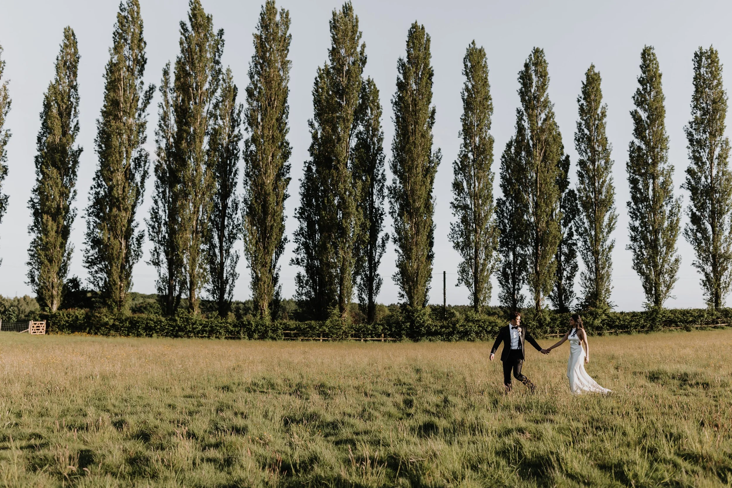 Couple walking through tree-lined sunset field