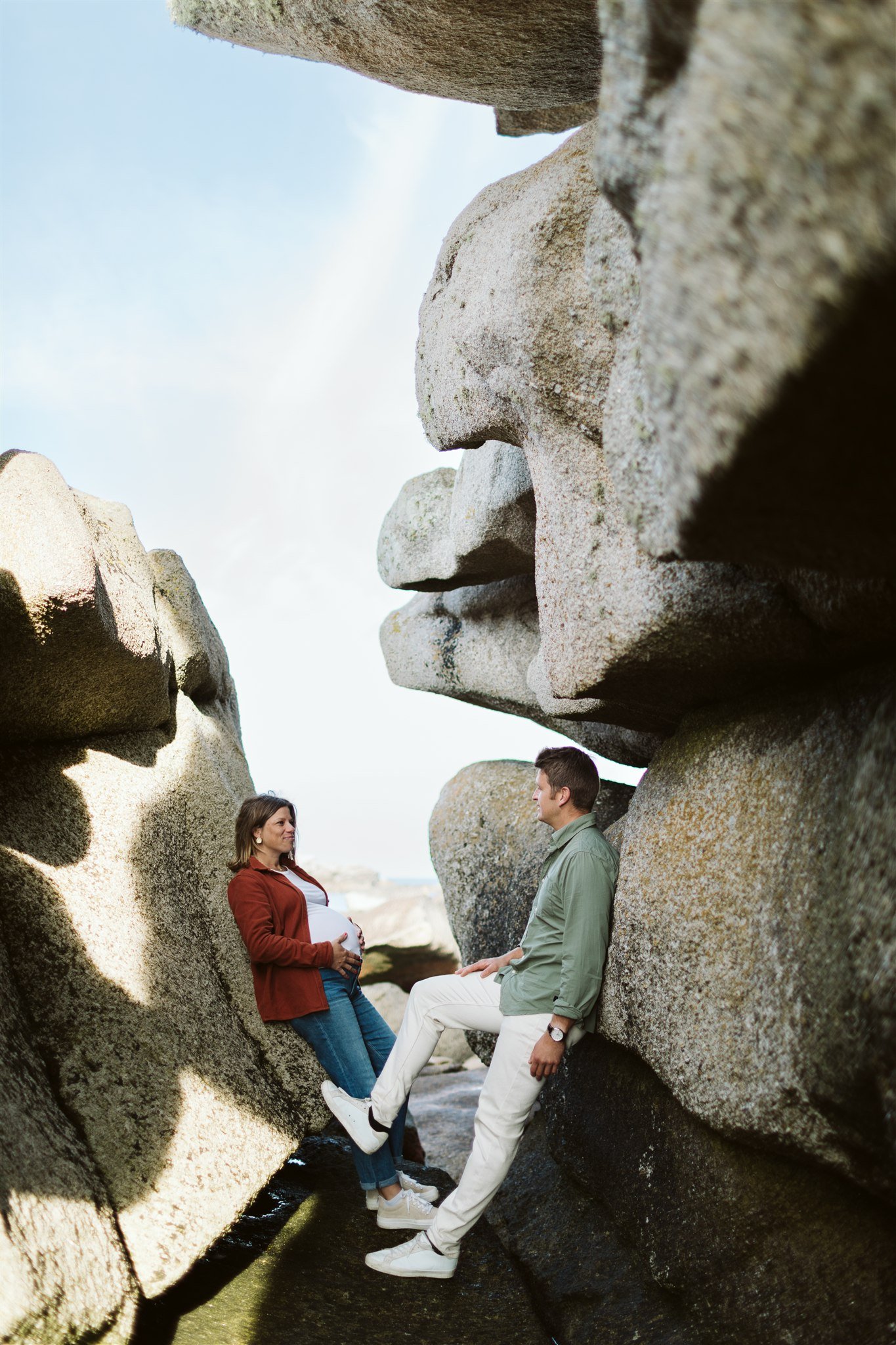 Un couple, dont la femme est enceinte, se retrouve entre de grandes roches près de la mer, en train de discuter.
