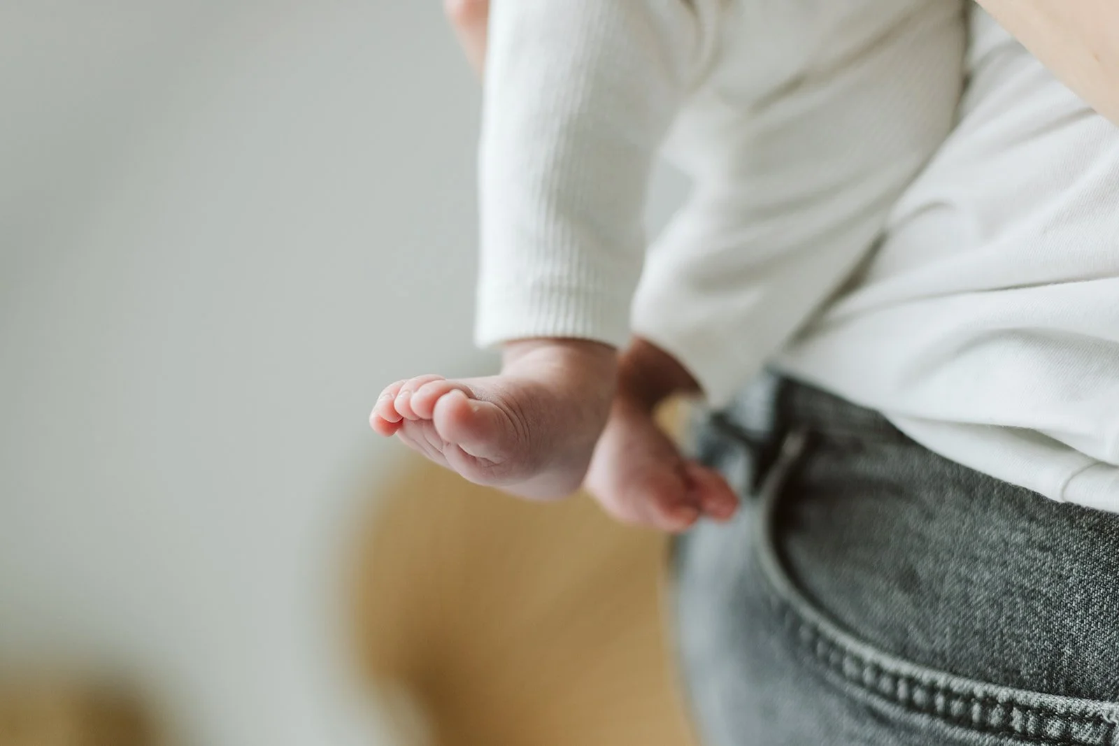 Main d'enfant tendue vers le bas, près de la taille, portant un pull blanc et un pantalon gris