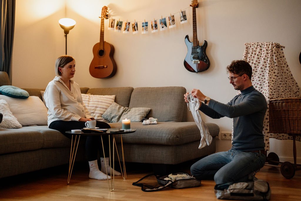Schwangeres Paar packt gemeinsam Kliniktasche für die Geburt, dokumentarische Fotografie