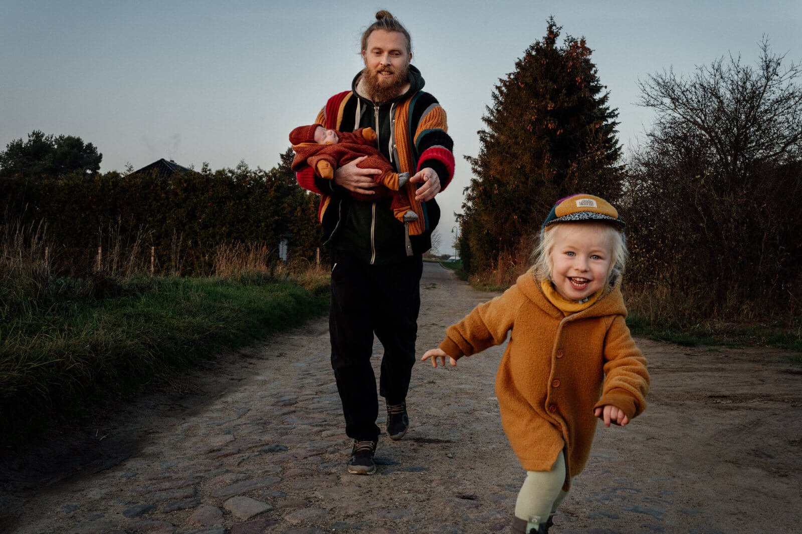 Kleinkind rennt vor Papa weg der ein baby auf dem arm hat