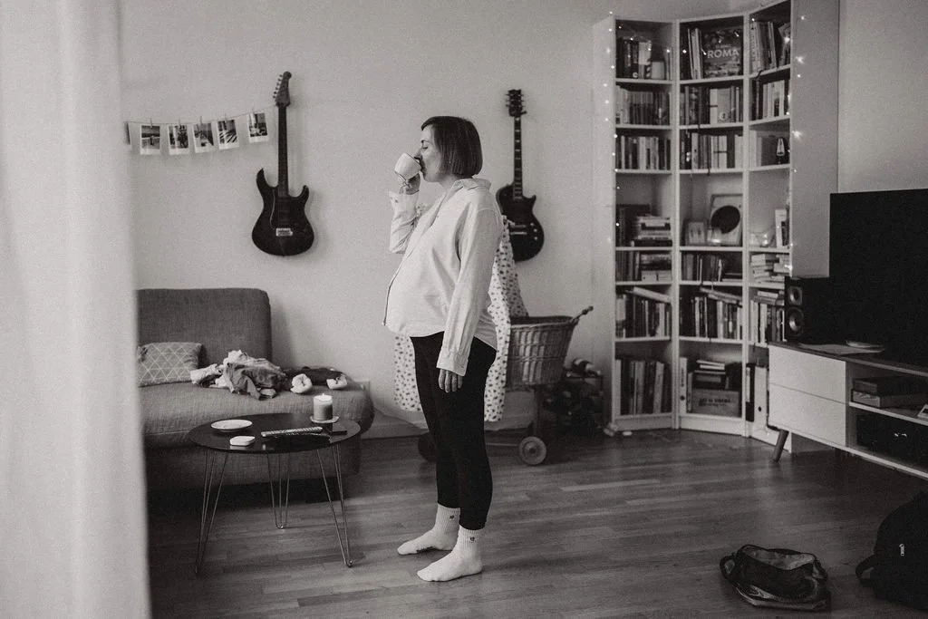 Schwangere Frau trinkt Kaffee allein zuhause, stiller Moment vor der Geburt