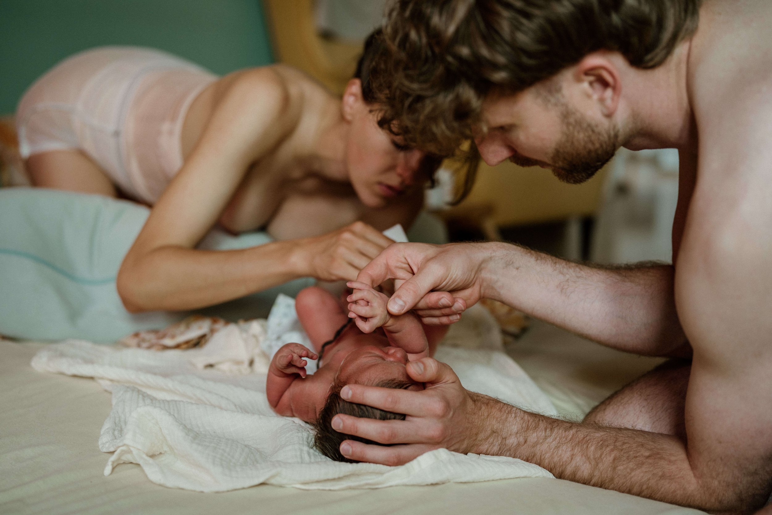 Vater hält hand von neugeborenen während die mama windel wechselt