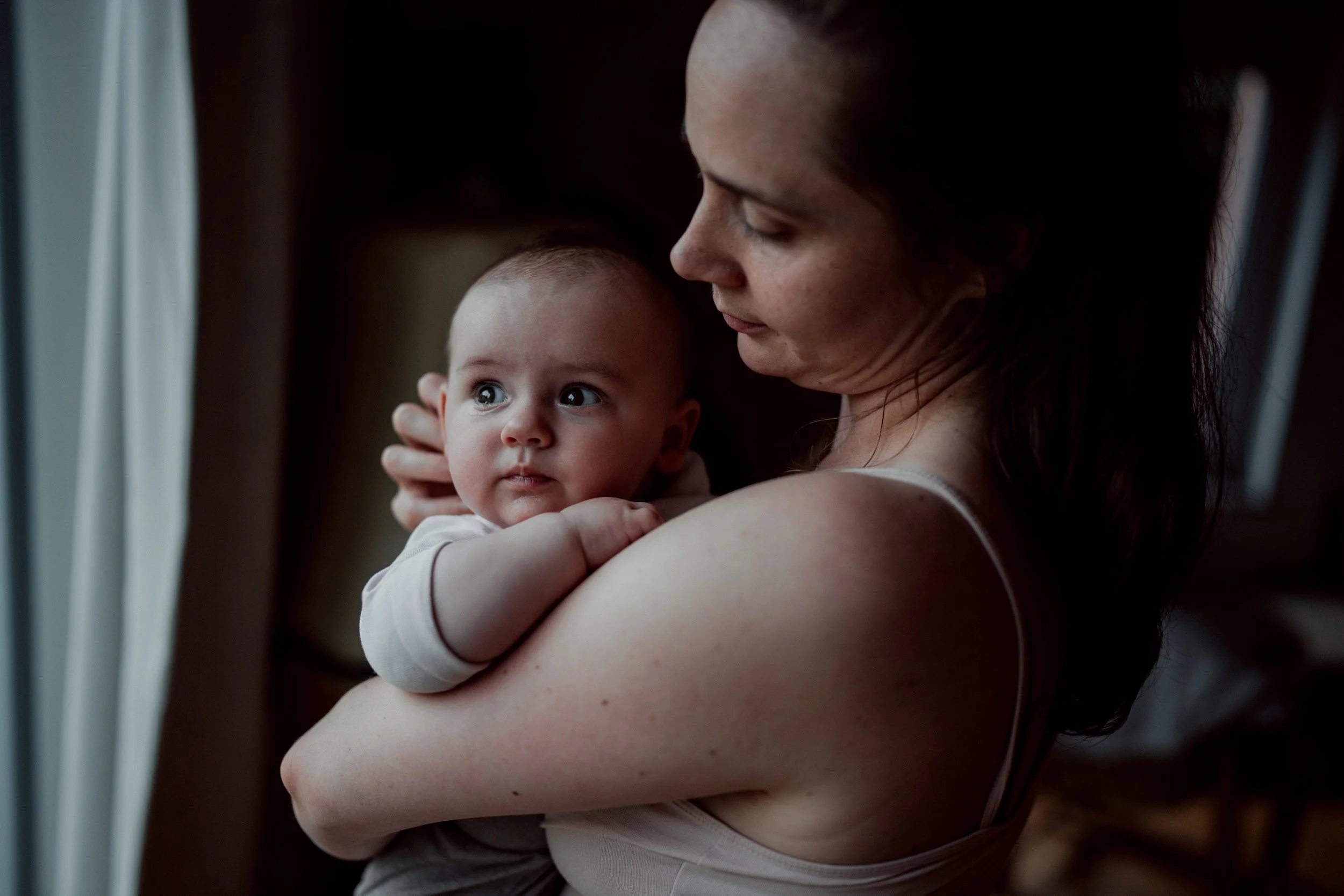 Mama haelt Baby auf arm und schaut es liebevoll an