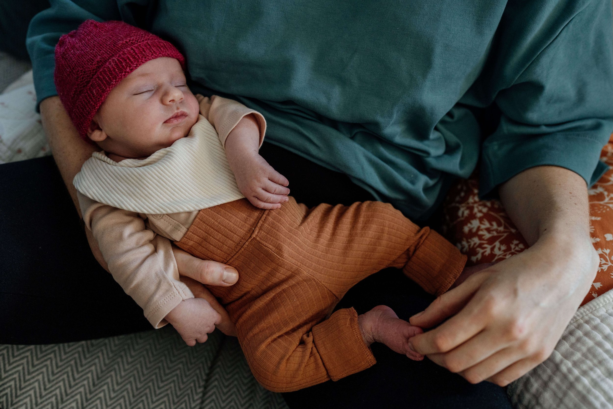 Baby schlafend in mamas armen auf dem sofa