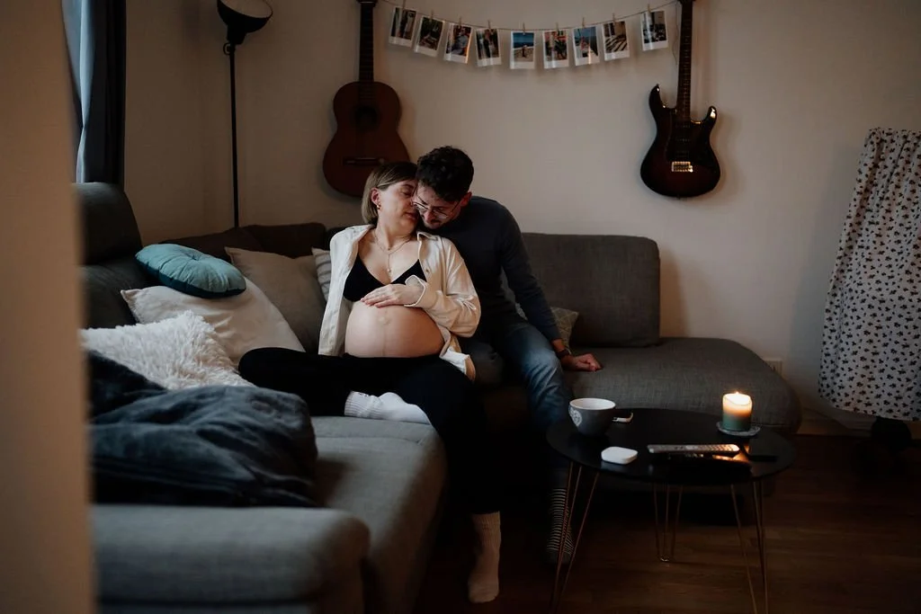 Schwangeres Paar kuschelt entspannt auf dem Sofa