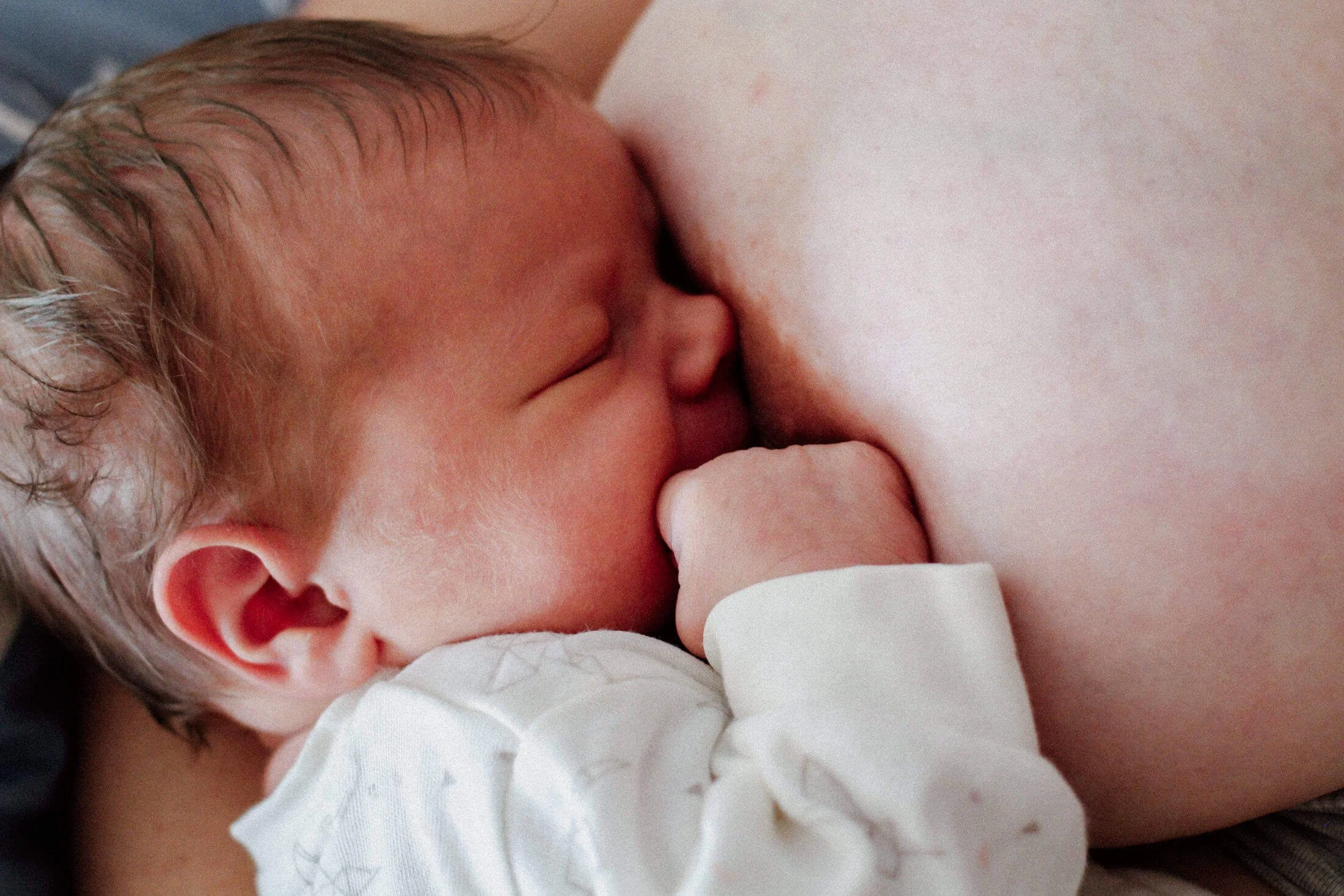 Nahaufnahme eines Neugeborenen an Mamas brust schlafend.