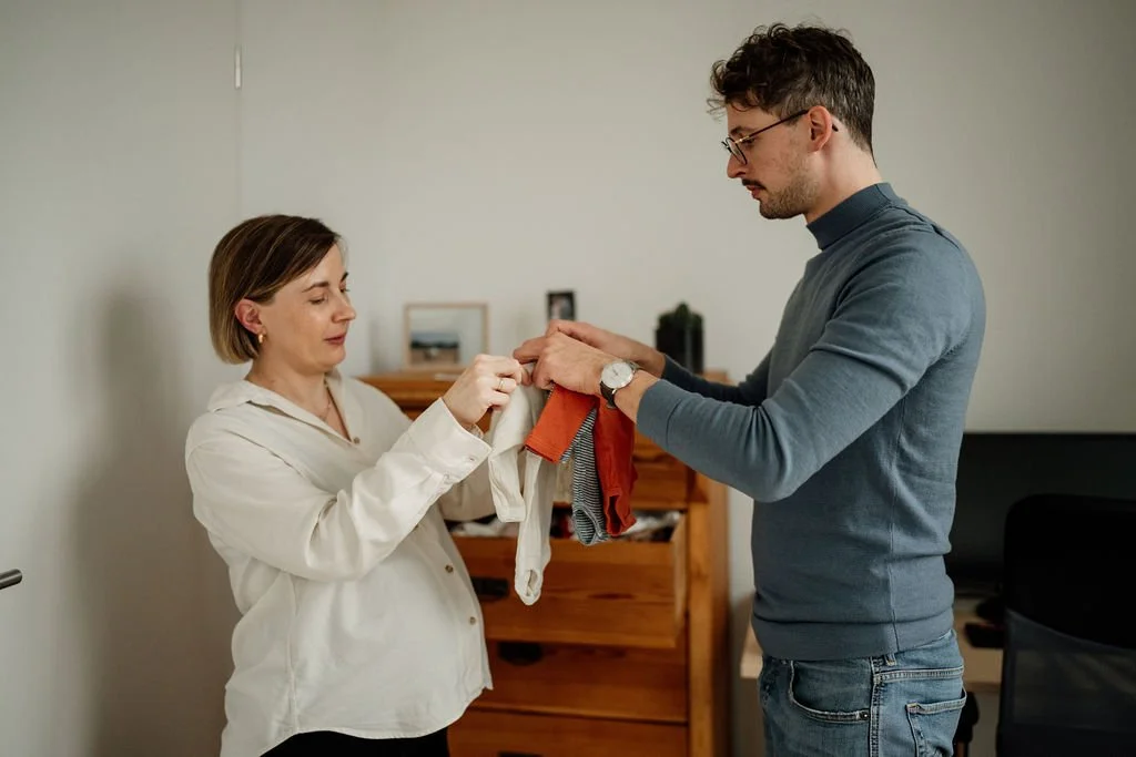 Mama und Papa packen Babykleidung für die Kliniktasche