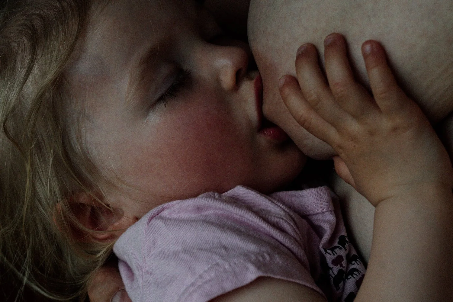 Kleinkind stillend und schlafend in Mamas Arm