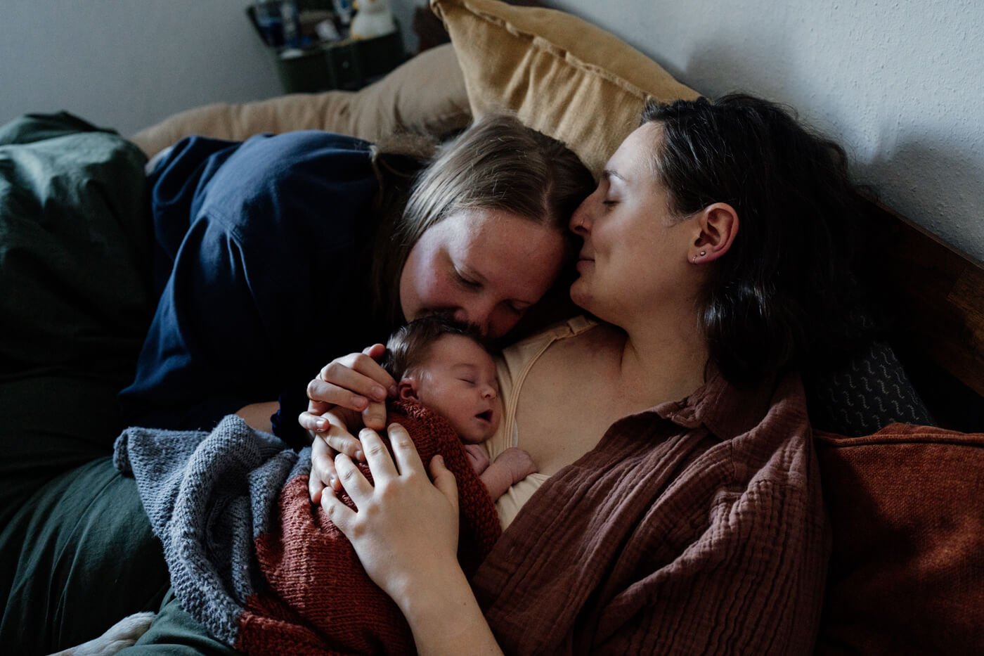neugeborenes schläft an mamas brust und liegt mit zweiter mama im wochenbett