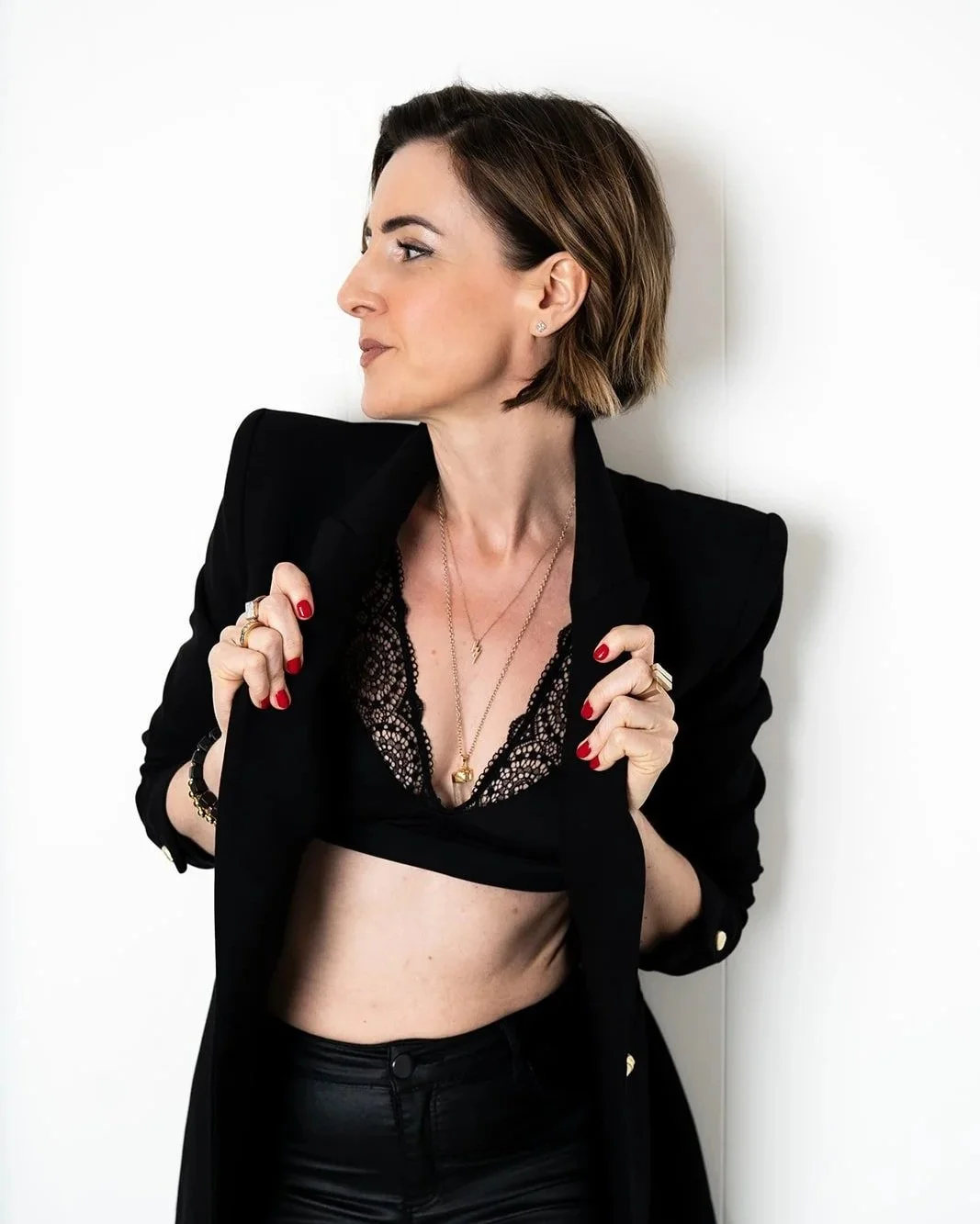 Lisa Moore, founder of House of Soul Sovereignty,wearing a black blazer holding the lapels looking to the left