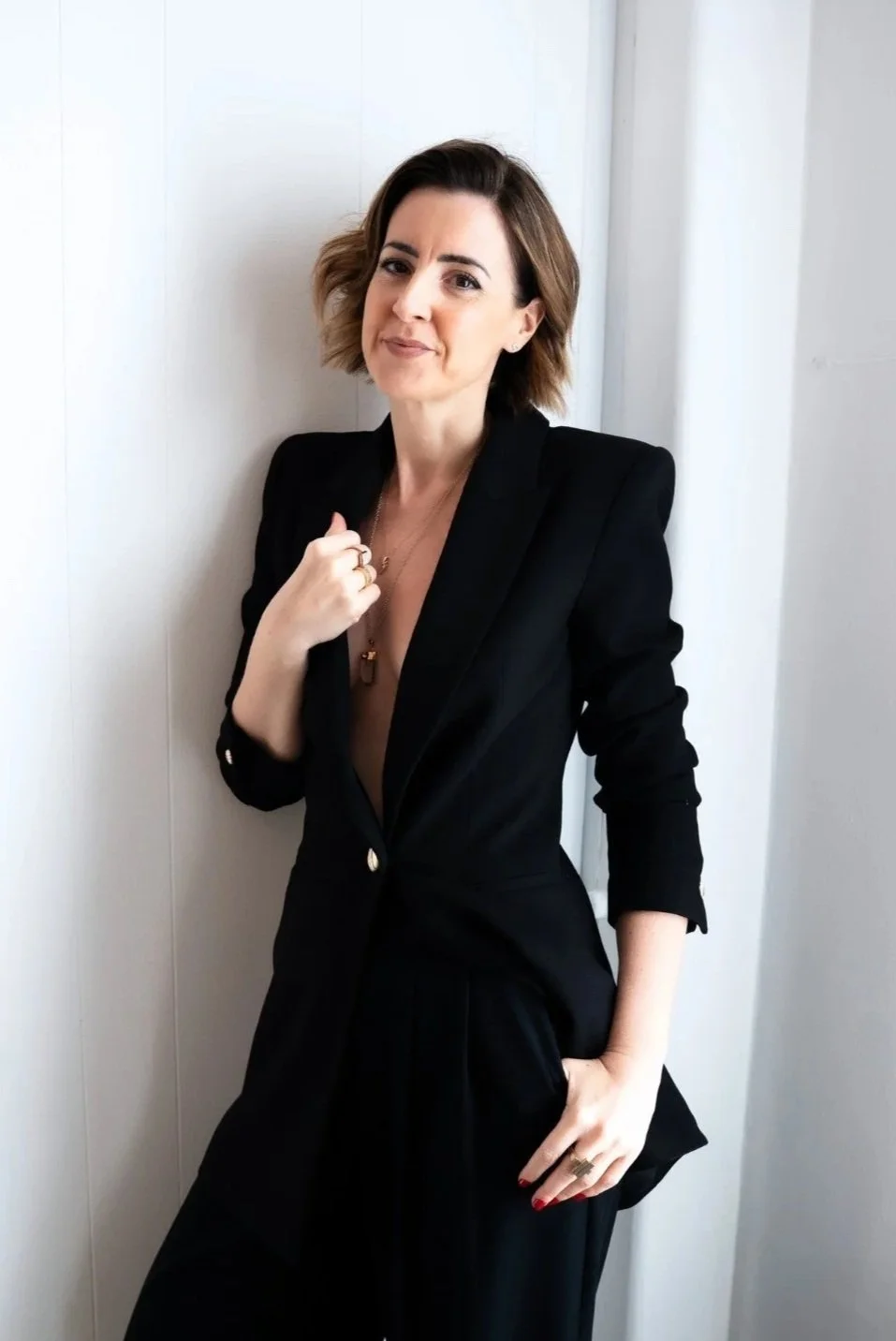 founder lisa wearing a black blazer holding the lapel and smiling to the camera