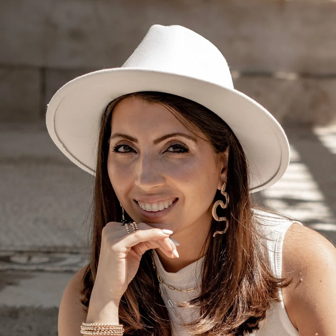 Cass, client of Lisa Moore, Sovereign Frequency Architect, smiling warmly in a white wide-brim hat and gold earrings, photographed outdoors in natural light