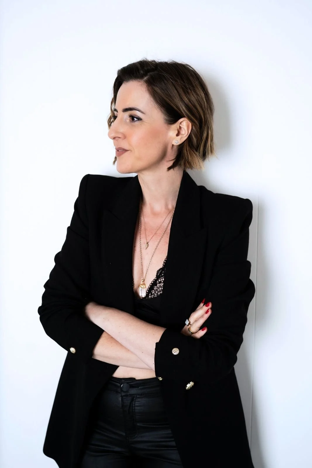 Lisa Moore, founder of House of Soul Sovereignty, wearing a black blazer with her arms crossed looking to the left